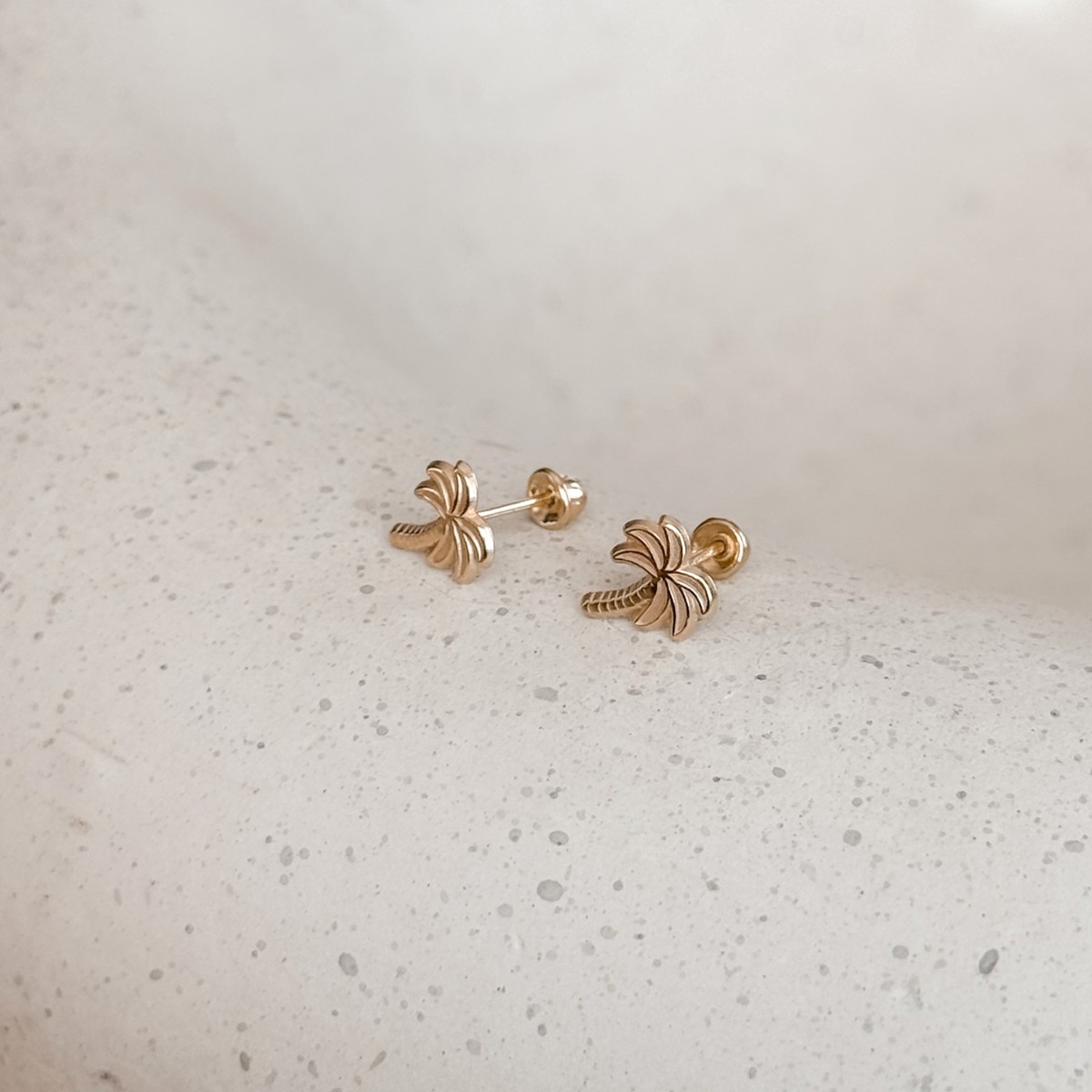 10K solid gold palm tree stud earrings with screw backs on a speckled stone dish – Liv Aura