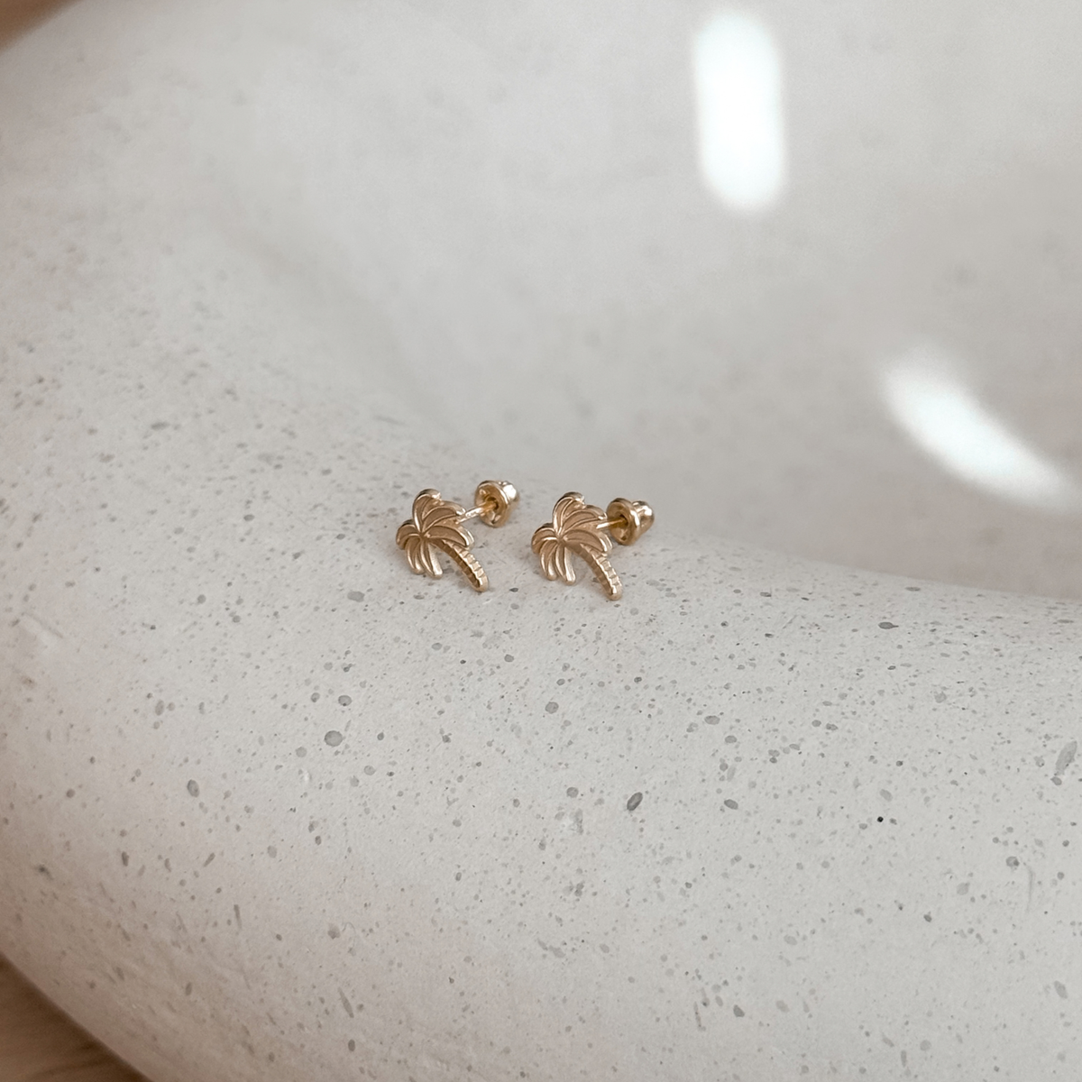 10K solid gold palm tree stud earrings on a stone dish, side view – Liv Aura