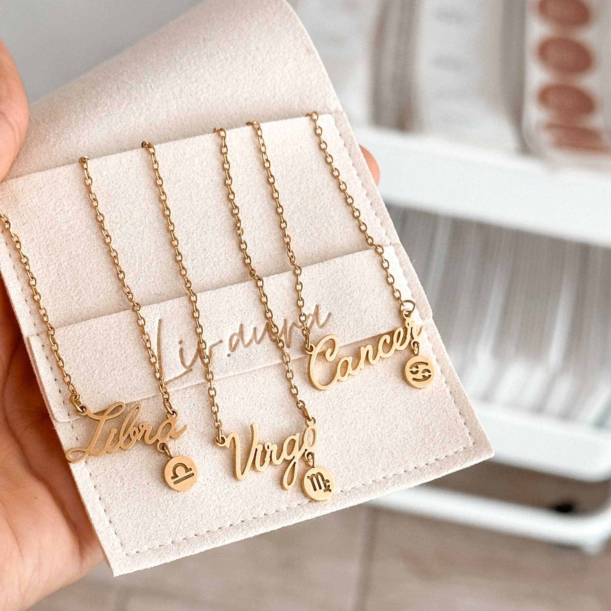 Multiple zodiac necklaces stacked together, showcasing different signs and layering styles