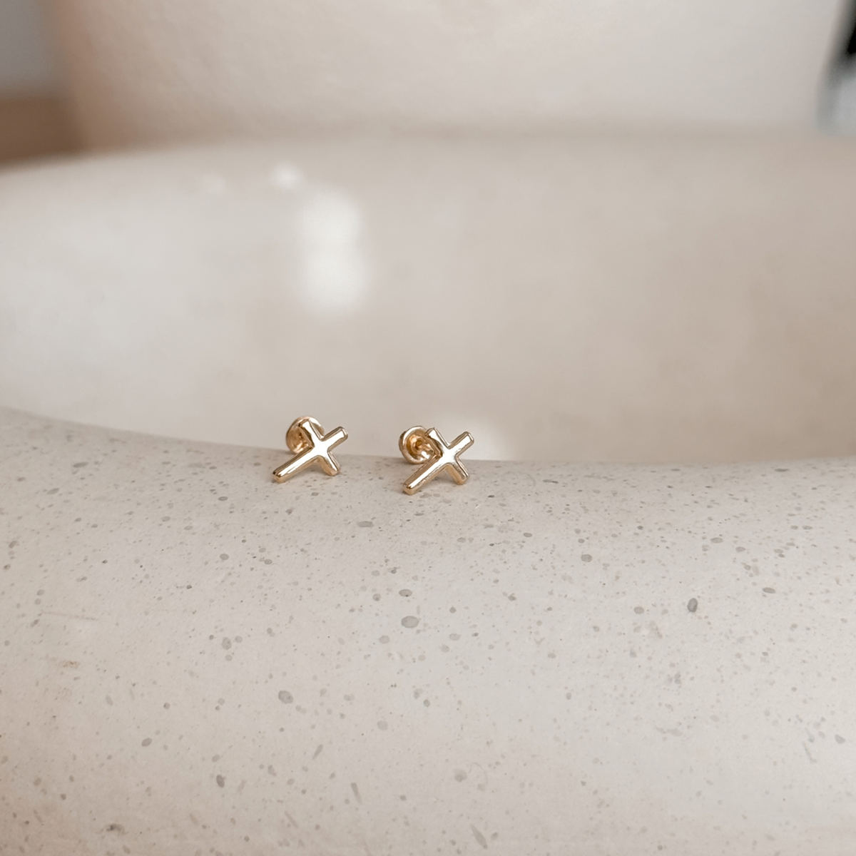 10K solid gold cross stud earrings with screw backs on a speckled stone dish – Liv Aura