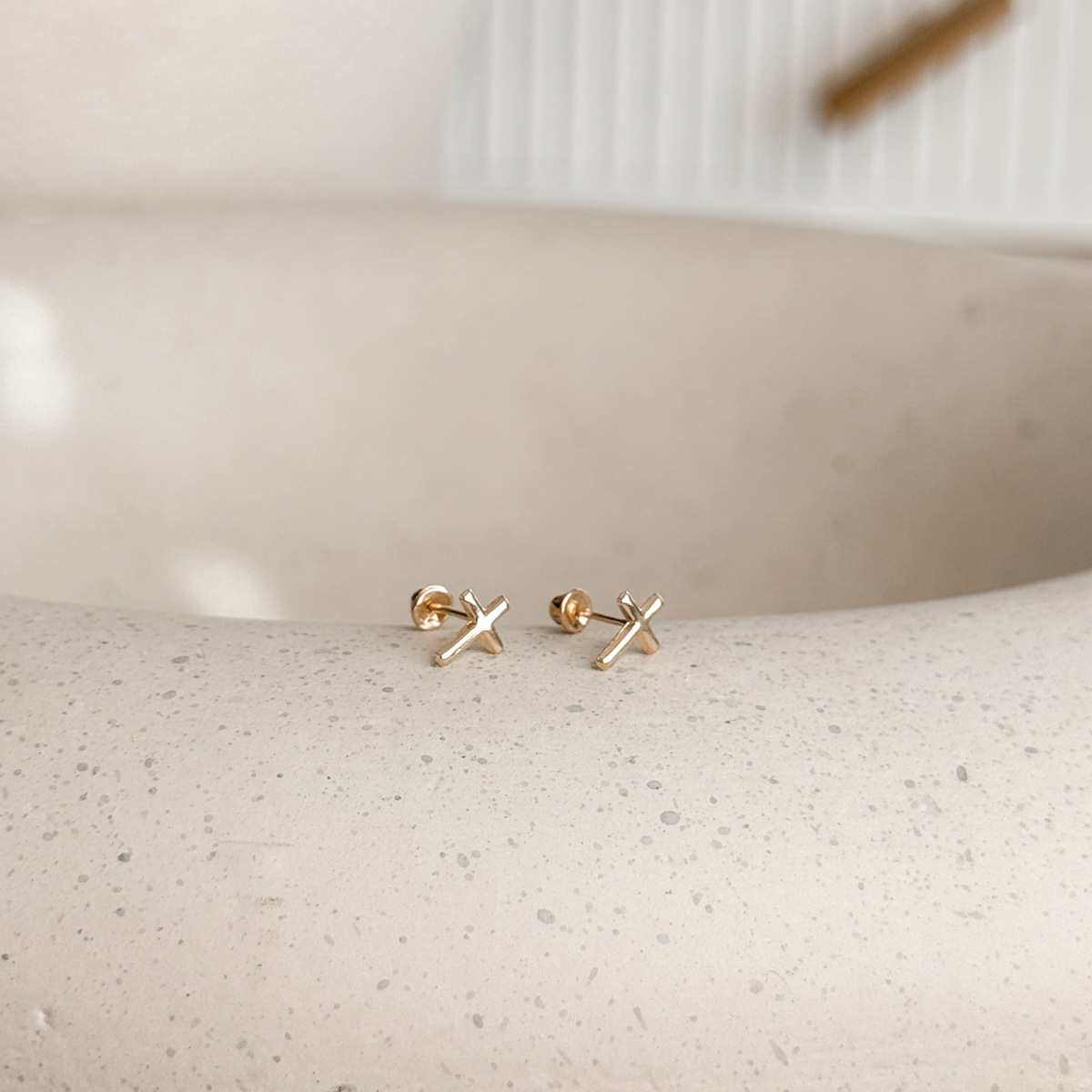 10K solid gold cross stud earrings on a stone dish, side view – Liv Aura