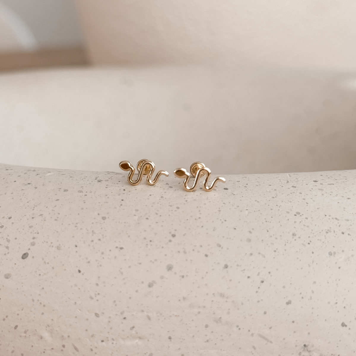 10K solid gold snake stud earrings with screw backs on a speckled stone dish – Liv Aura