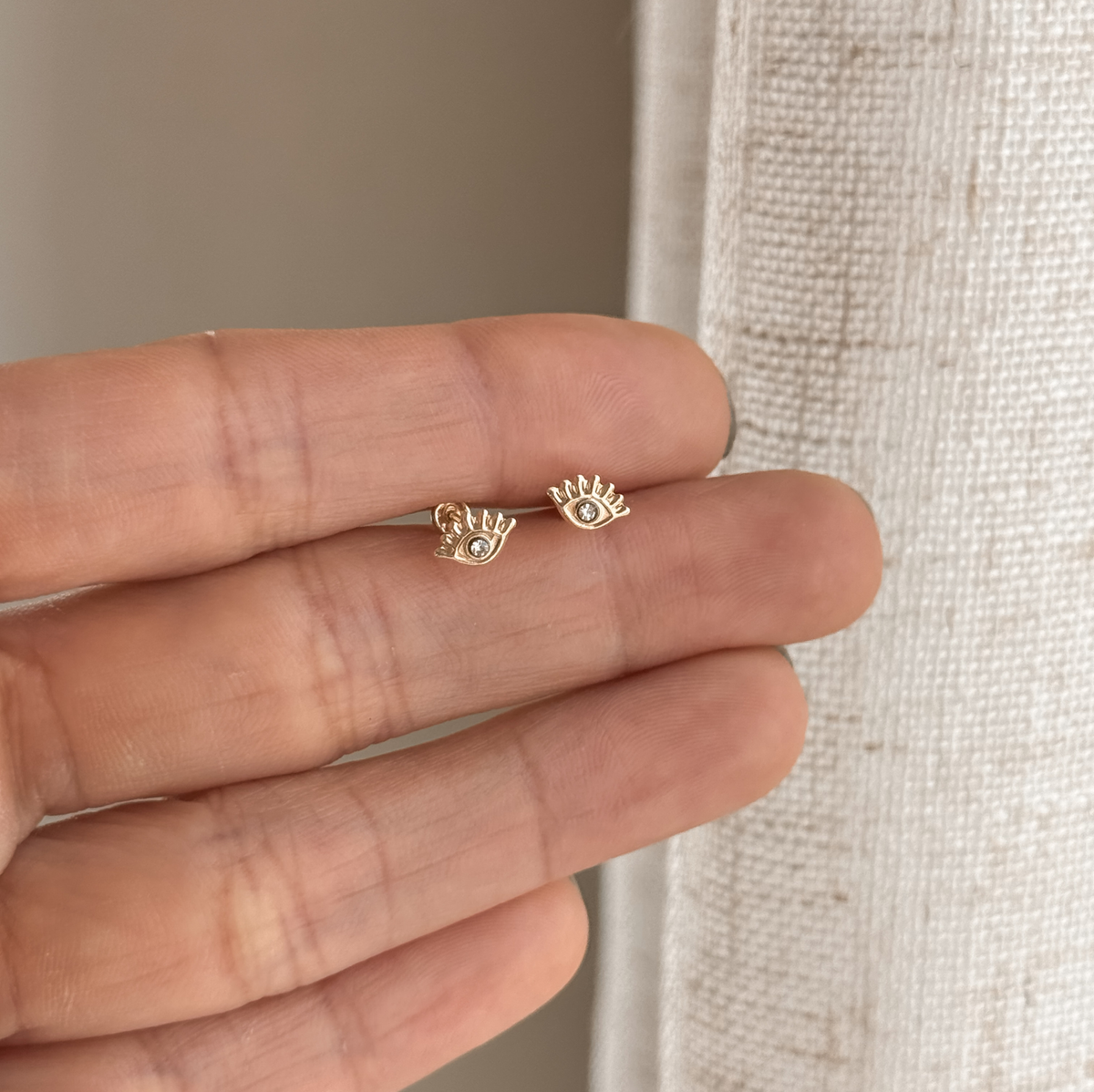 10K solid gold evil eye stud earrings held in hand to show the size – Liv Aura