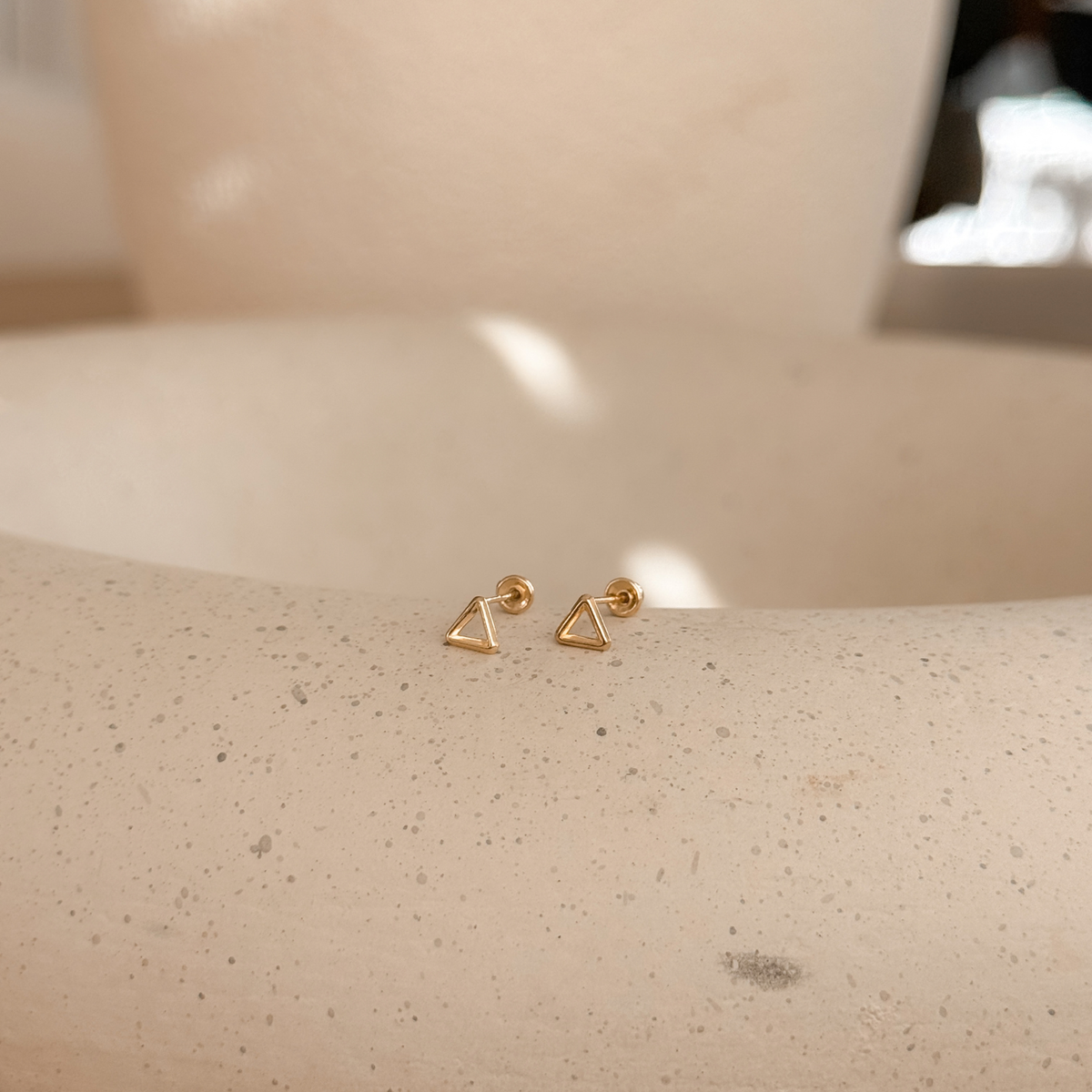 10K solid gold open triangle stud earrings on a stone dish, side view – Liv Aura