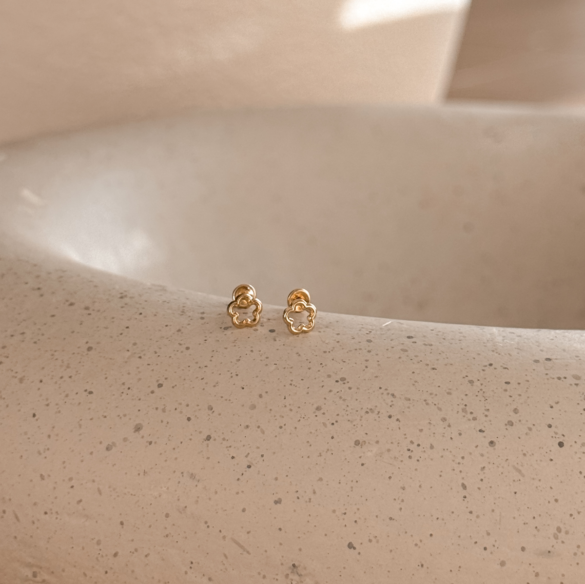 10K solid gold flower stud earrings on a speckled stone dish – Liv Aura
