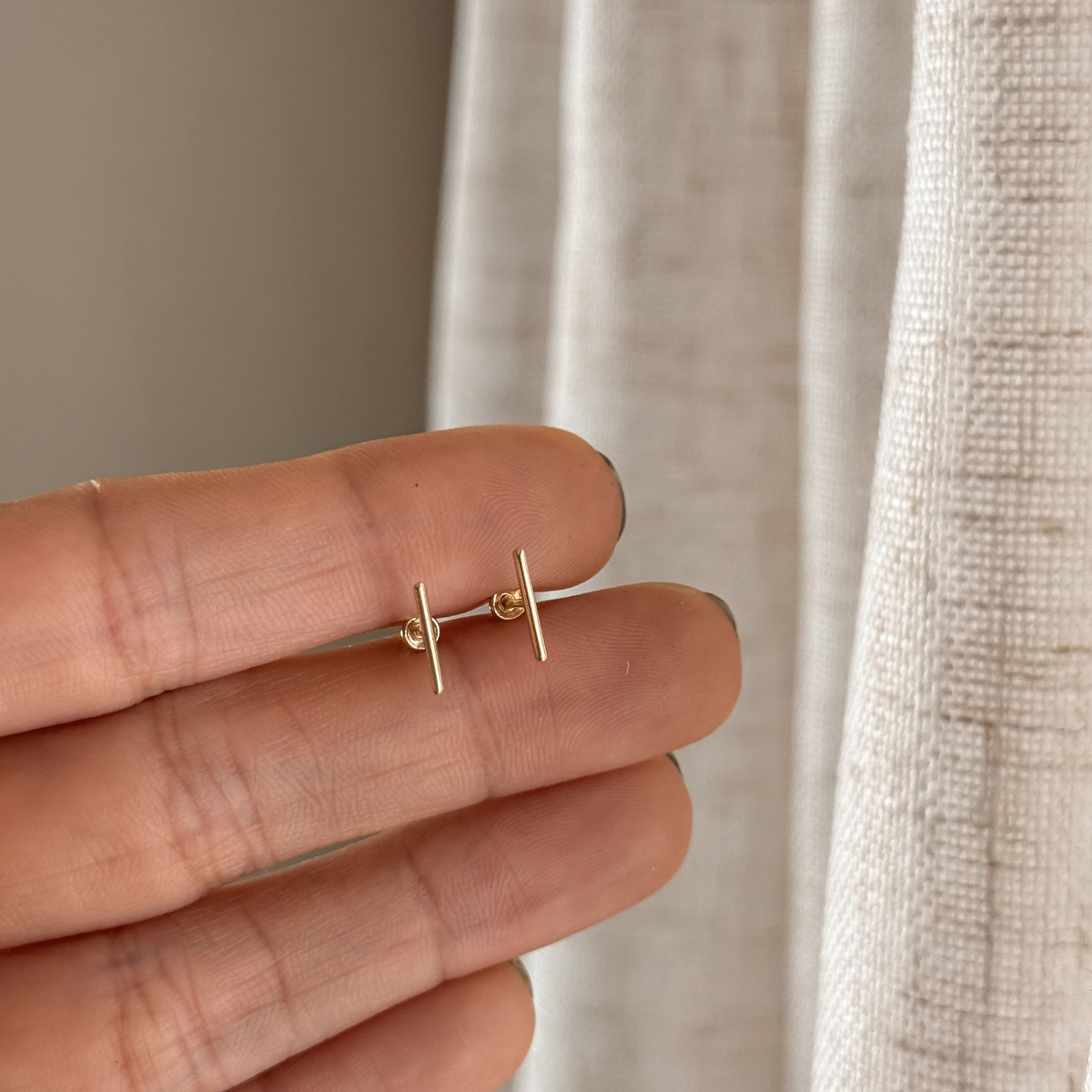 10K solid gold bar stud earrings held in hand to show the size – Liv Aura