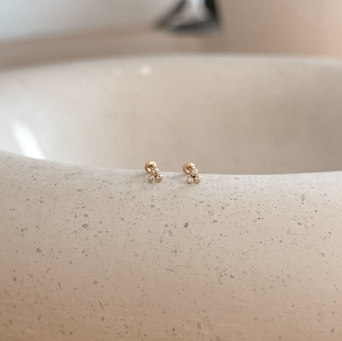 10K solid gold CZ trio bezel stud earrings on a speckled stone dish – Liv Aura