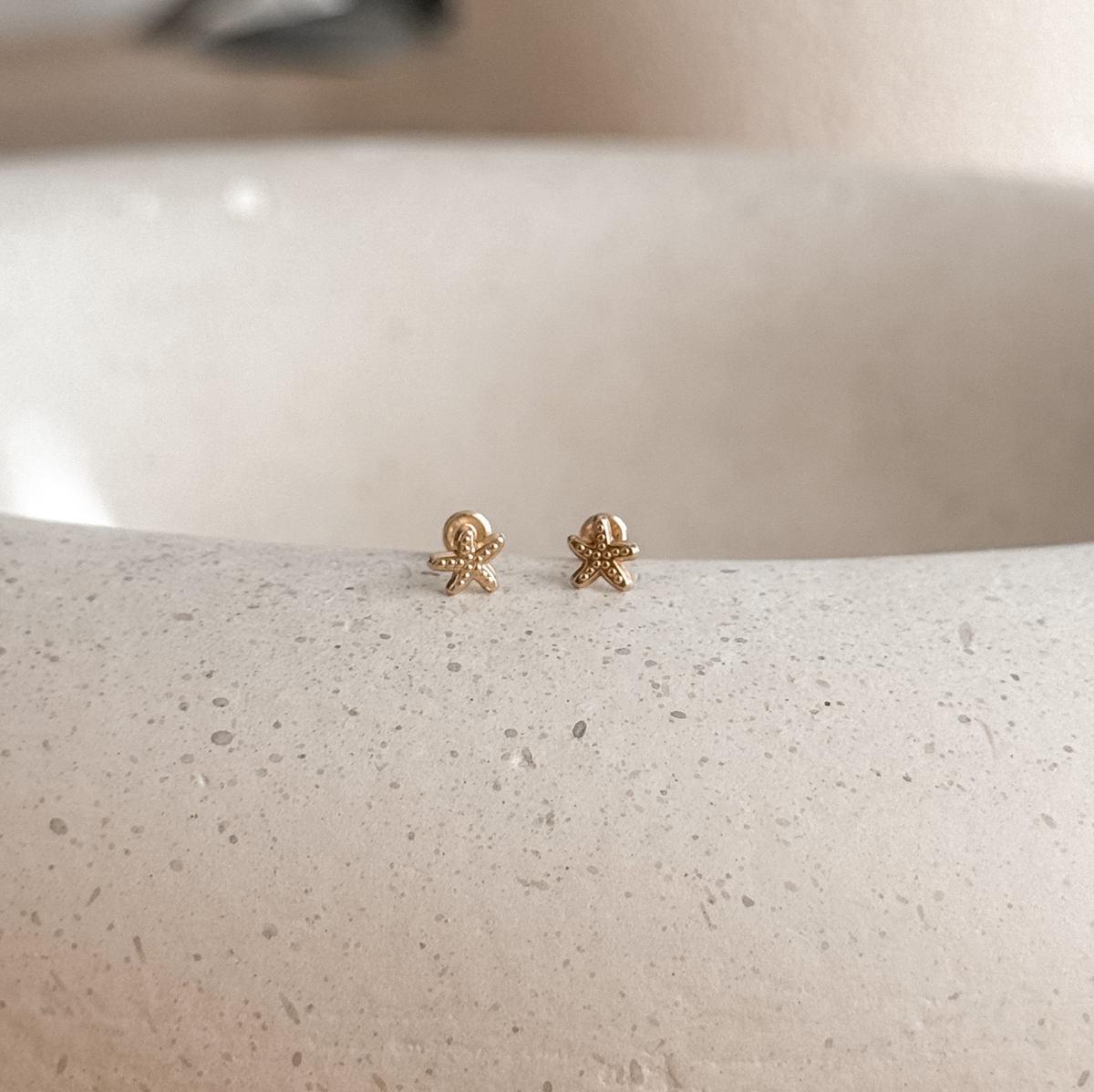 10K solid gold starfish stud earrings on a speckled stone dish – Liv Aura
