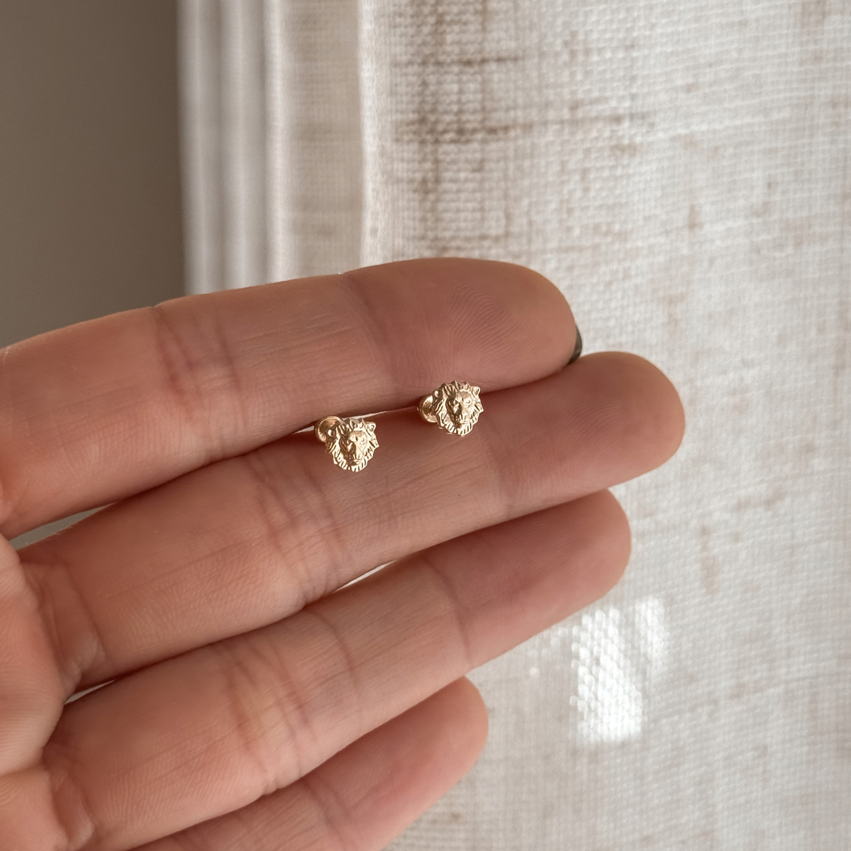10K solid gold lion stud earrings held in hand to show the size – Liv Aura