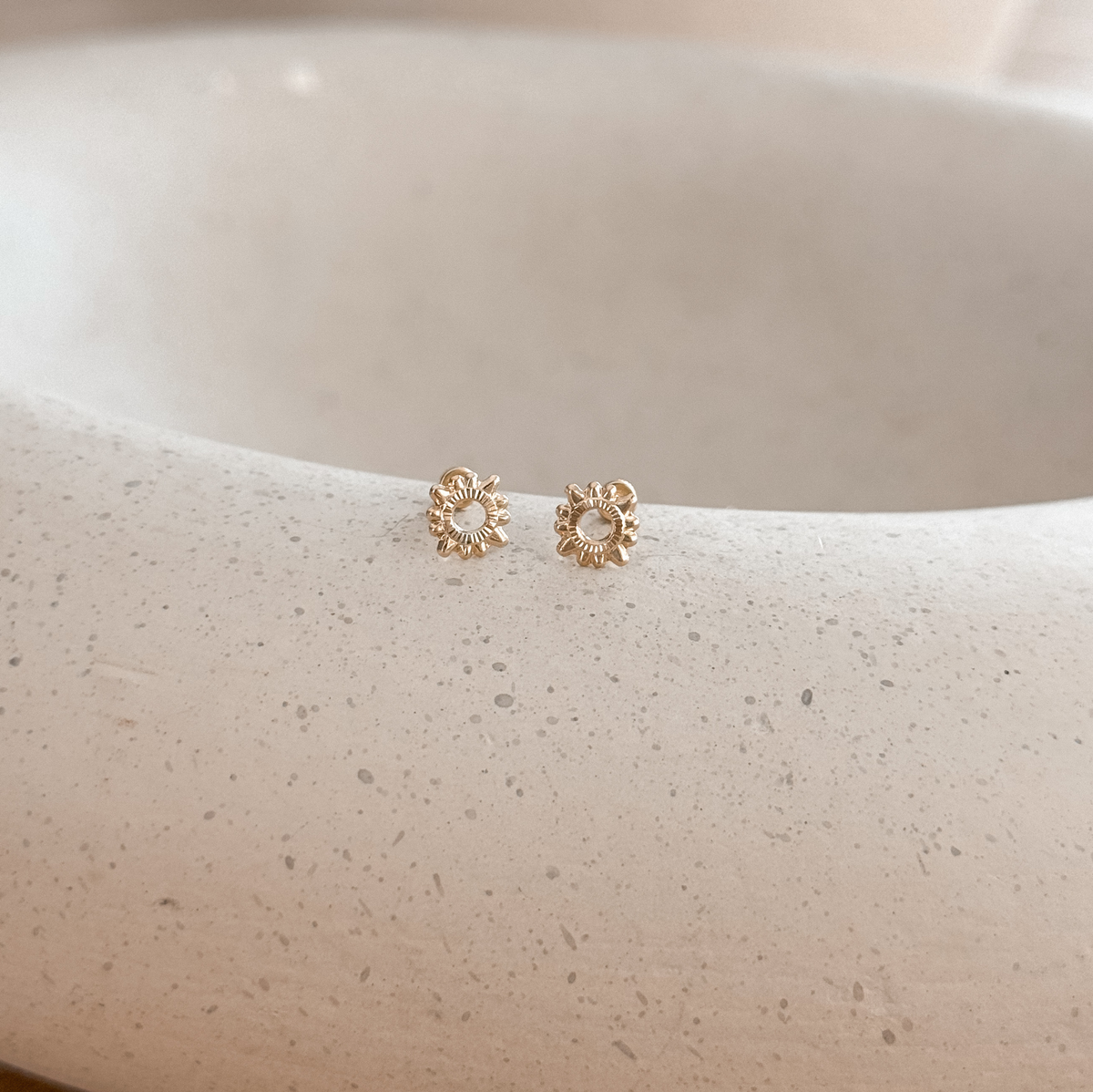 10K solid gold sun stud earrings on a speckled stone dish – Liv Aura