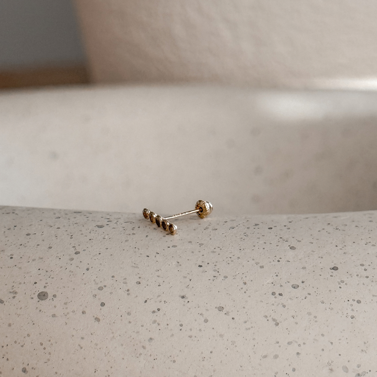 10K solid gold slim CZ bar stud earring on a stone dish, side view – Liv Aura