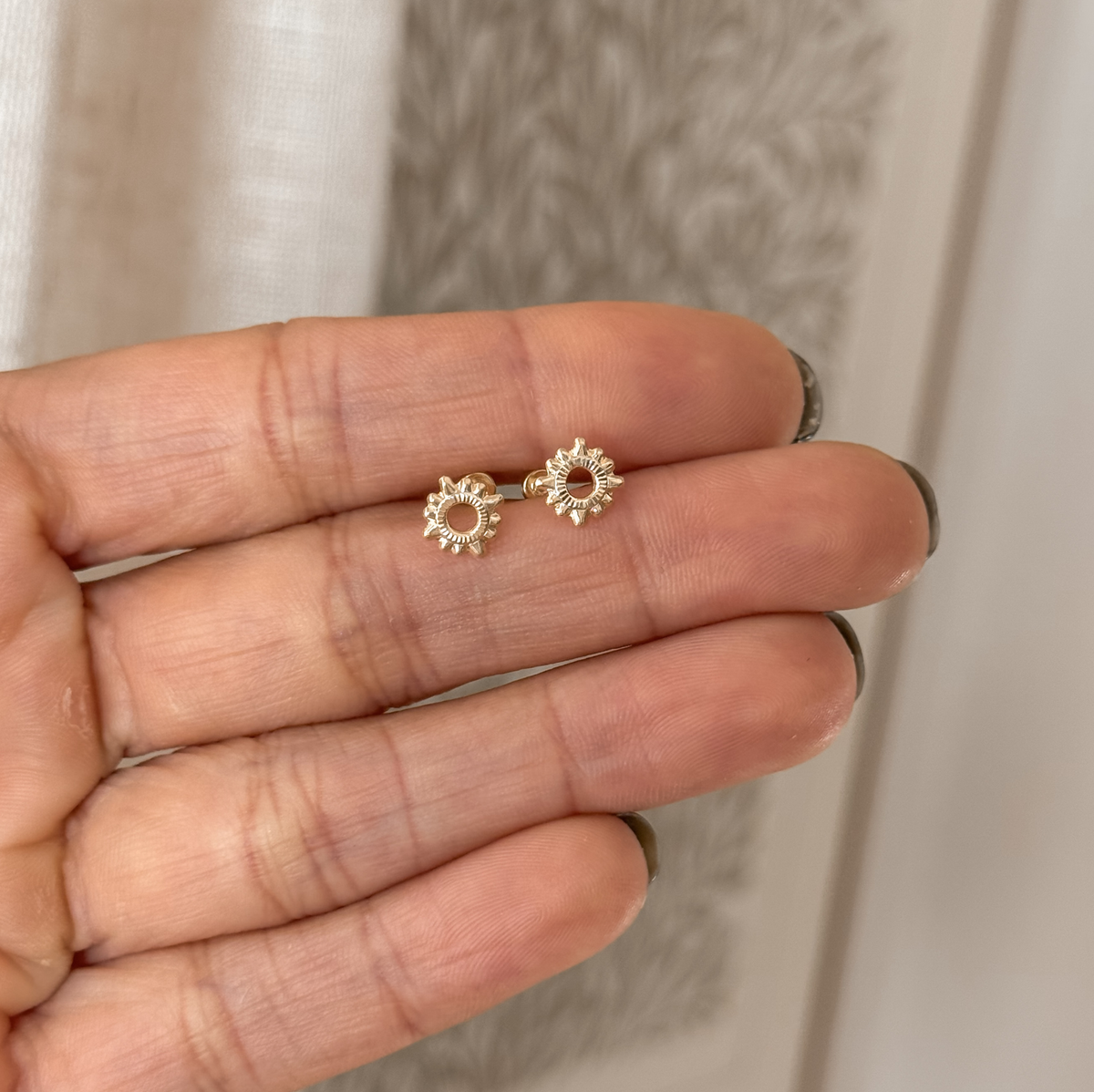 10K solid gold sun stud earrings held in hand to show the size – Liv Aura