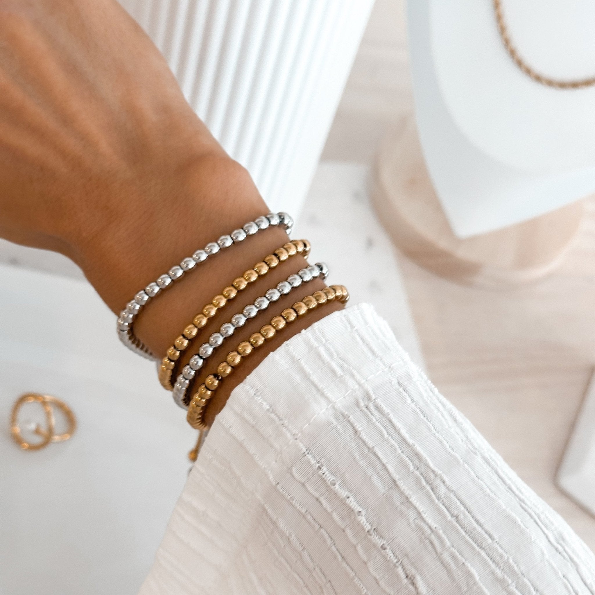 Adjustable gold and silver bead bracelets shown stacked on wrist