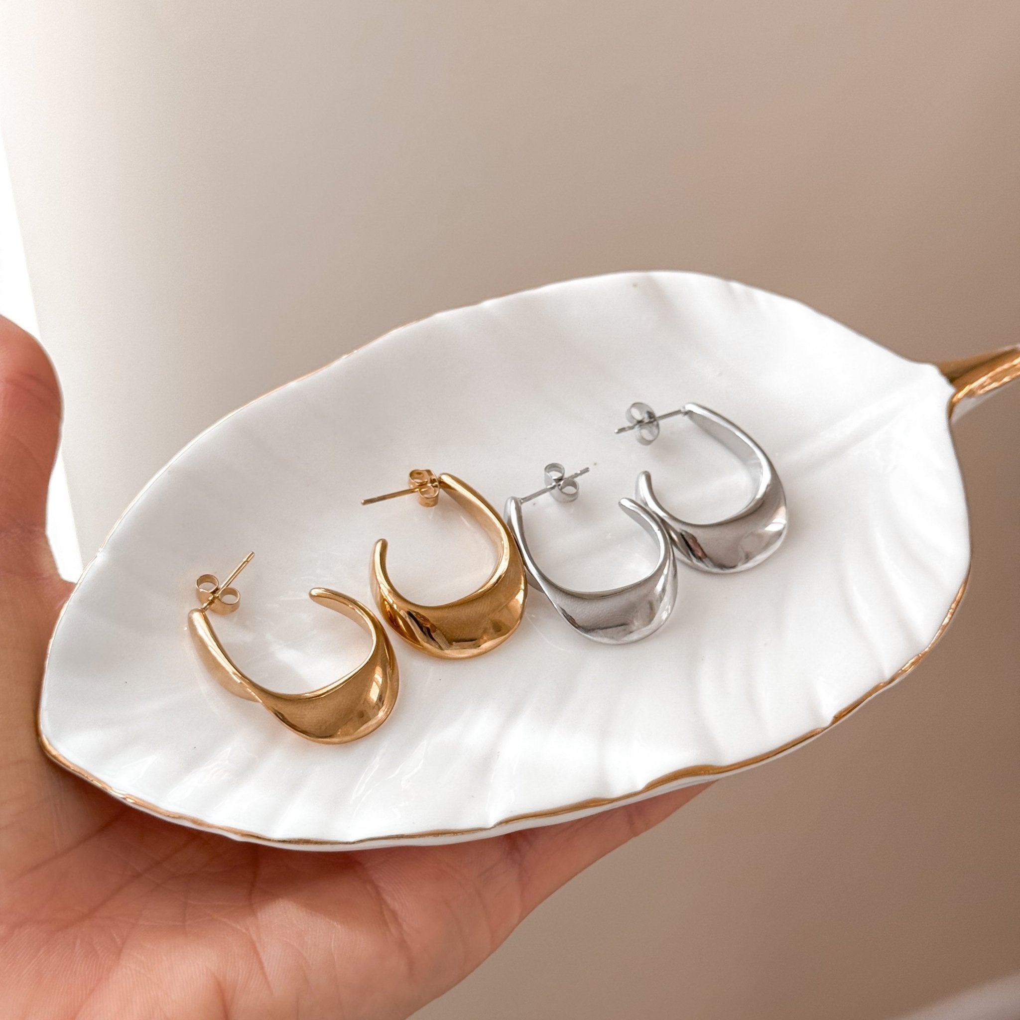 Minimalist hoops in both gold and silver tones placed on woven natural background