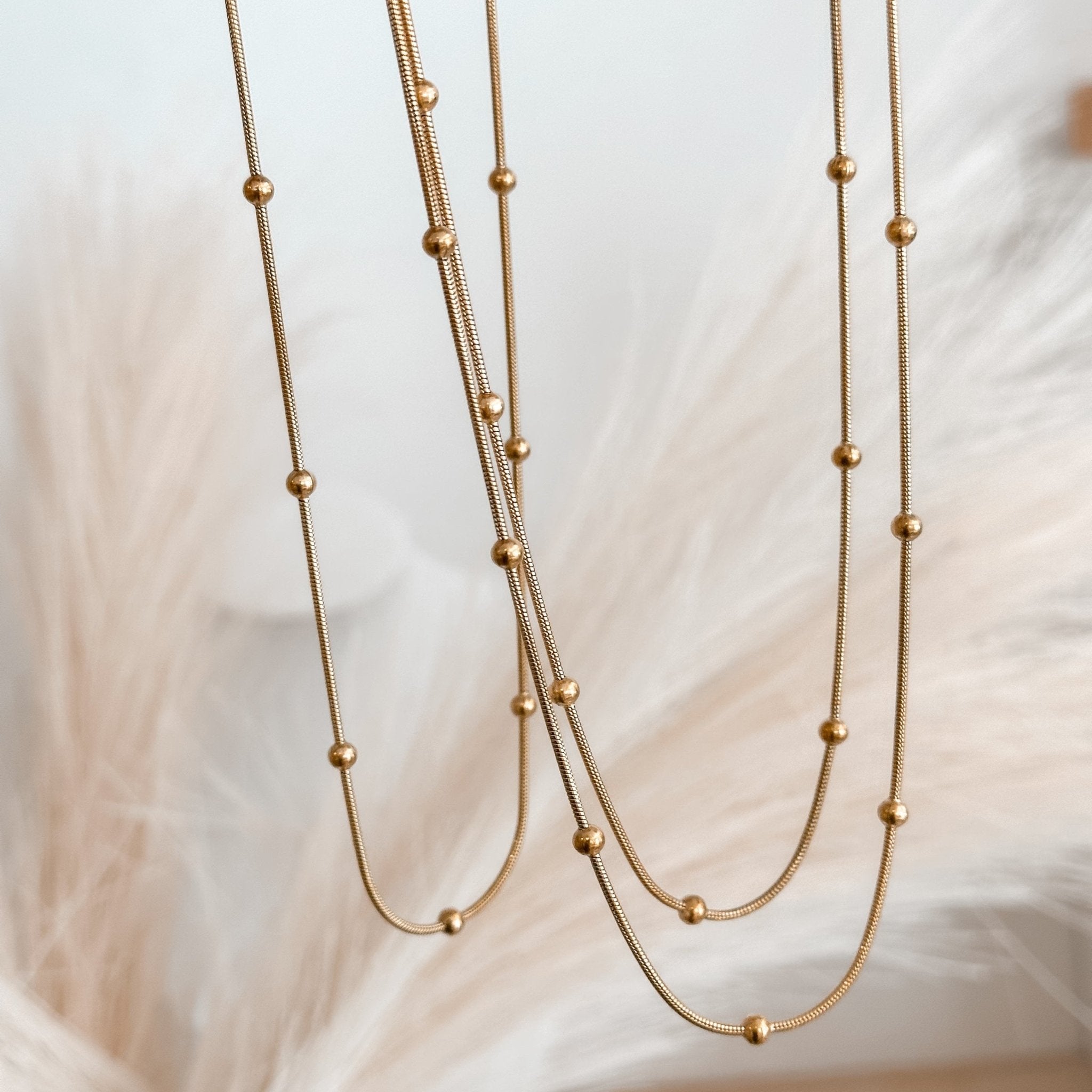 Close-up of gold snake beaded necklace on soft fabric – minimalist waterproof layering chain