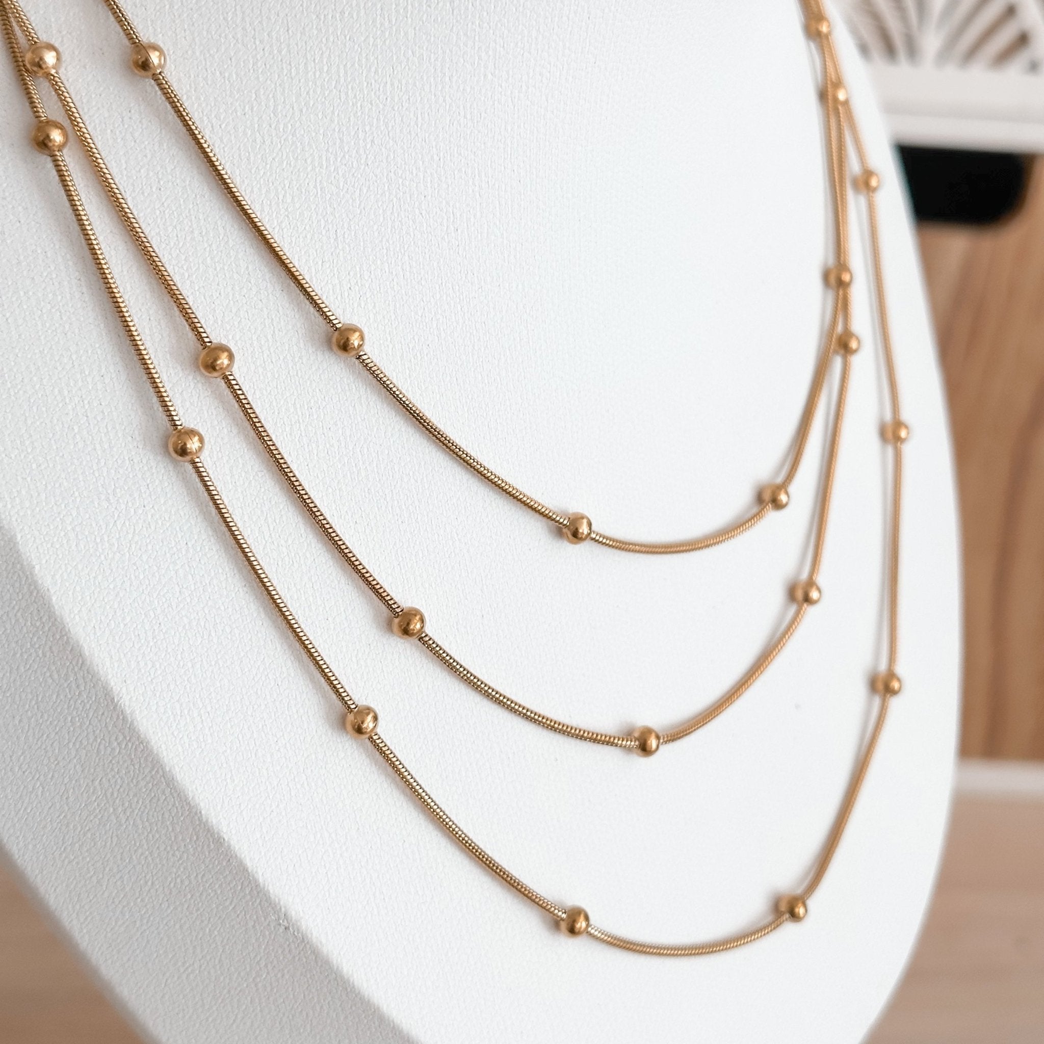 Layered 18K gold-plated beaded necklaces displayed on bust – delicate and adjustable design