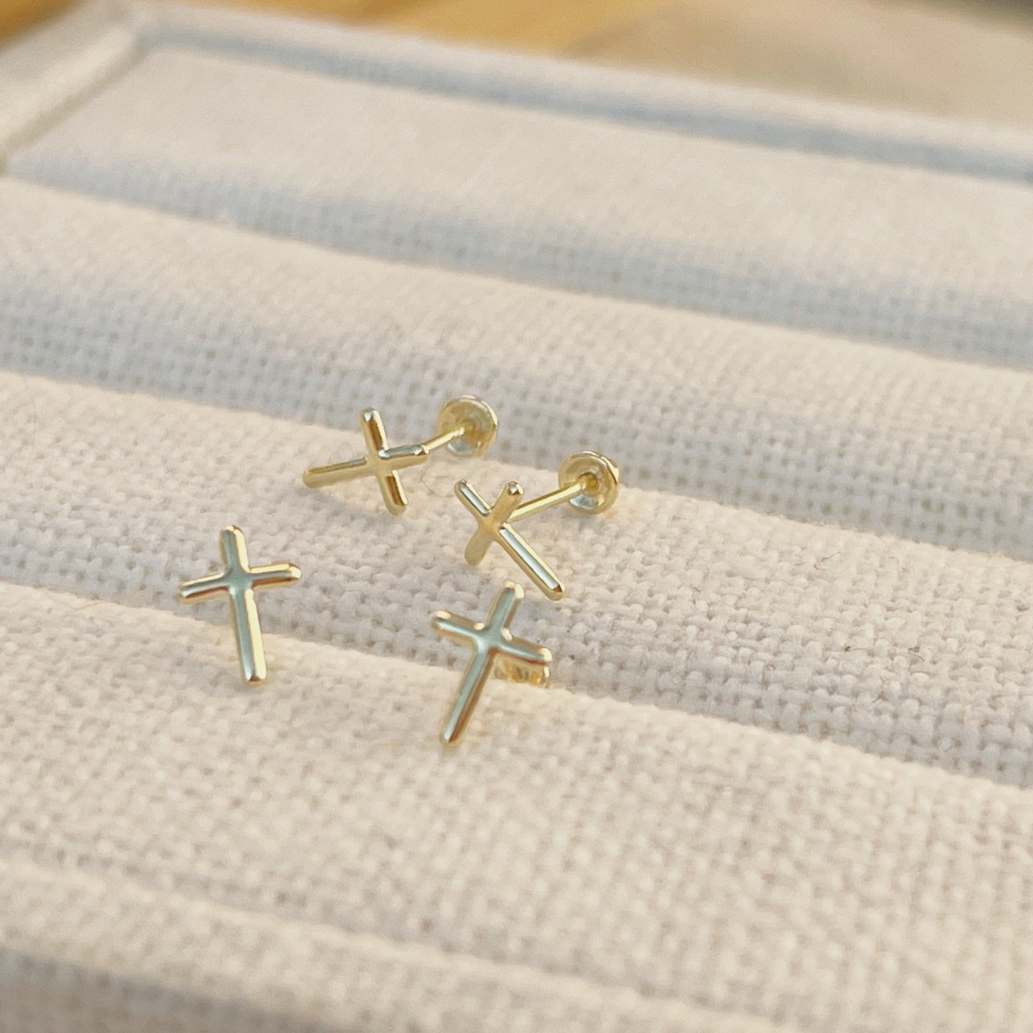 Tiny cross earrings in 10K solid gold on neutral fabric, minimalist dainty studs