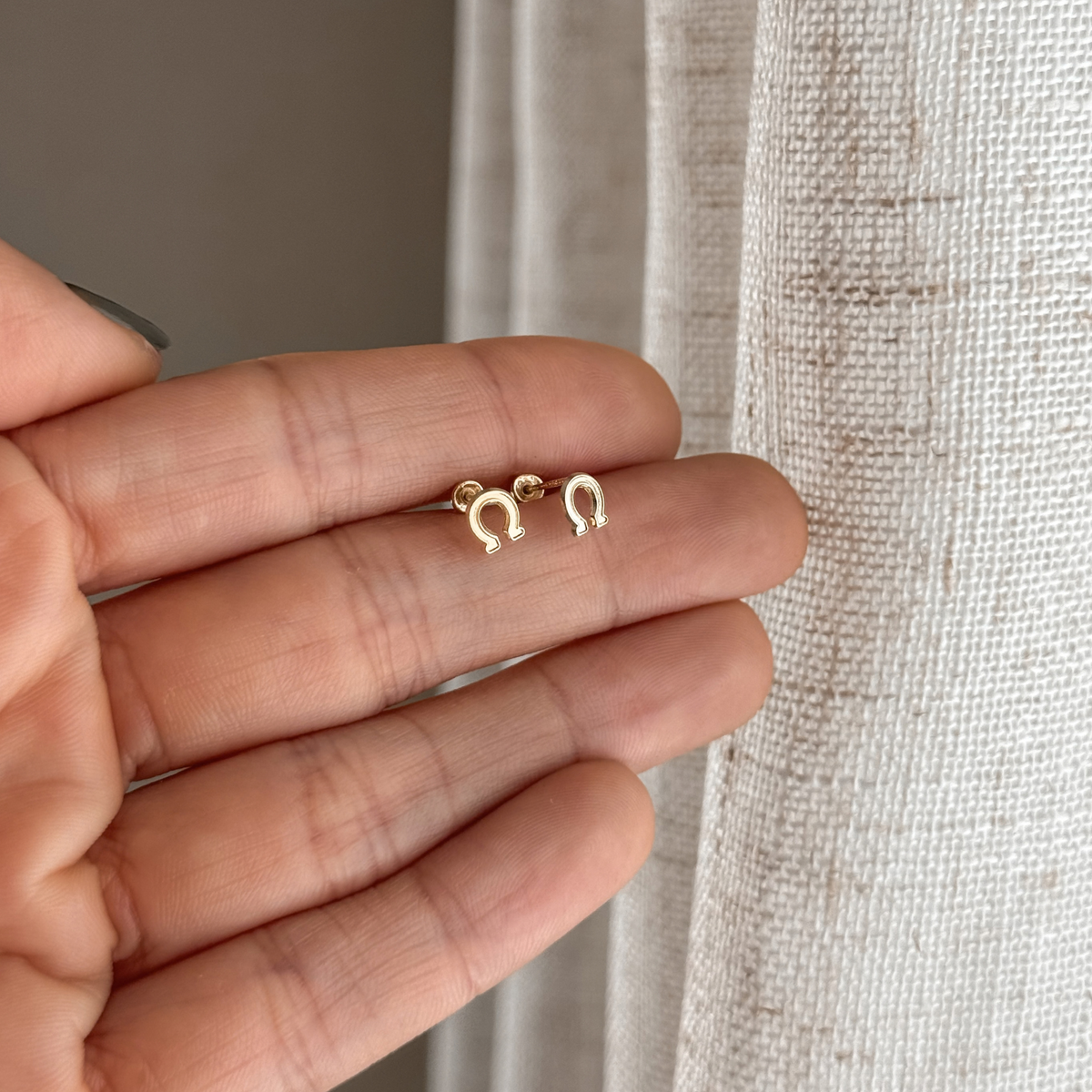 10K solid gold horseshoe stud earrings held in hand to show the size – Liv Aura