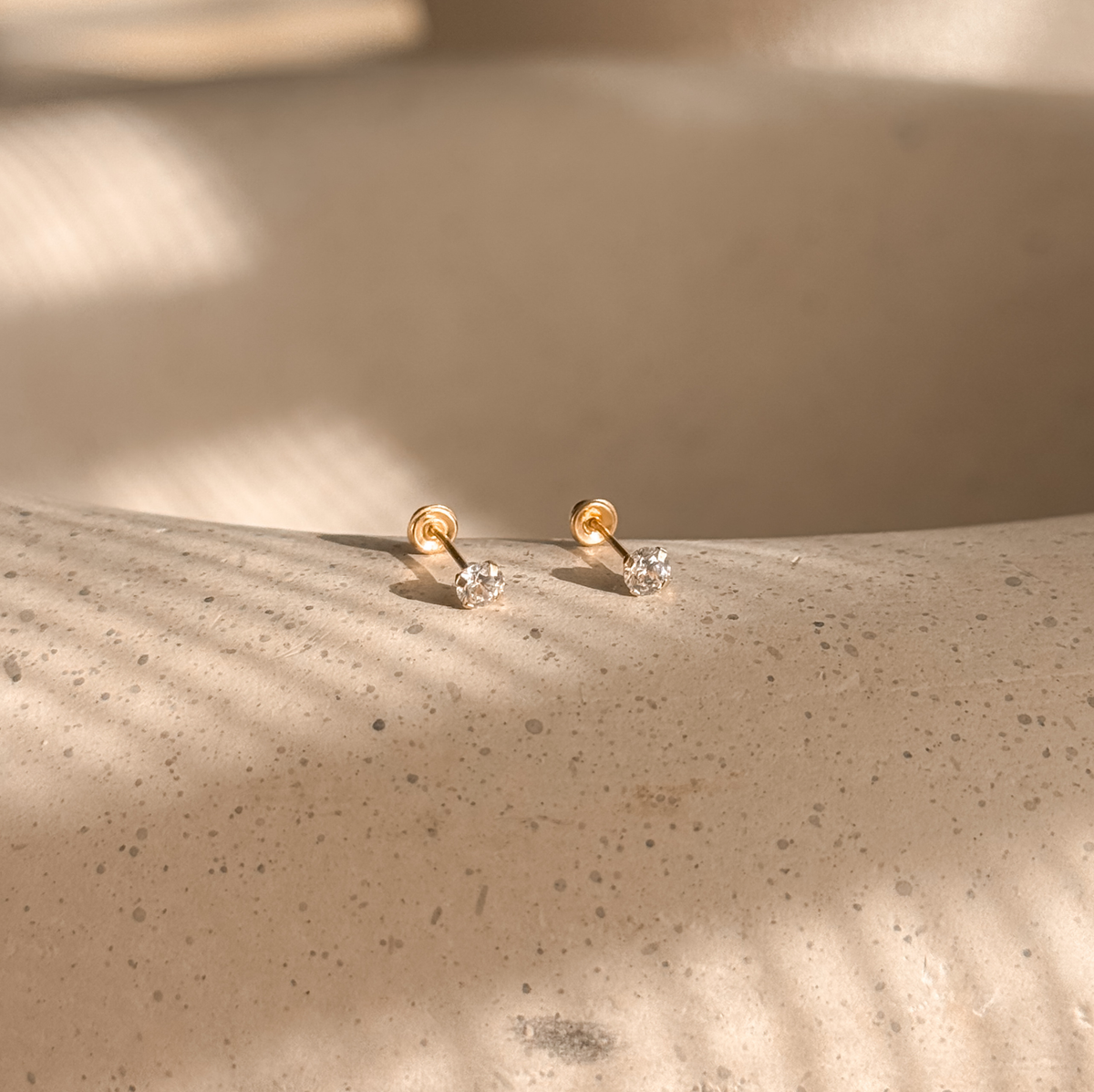 10K solid gold 3mm CZ solitaire stud earrings on a speckled stone dish – Liv Aura