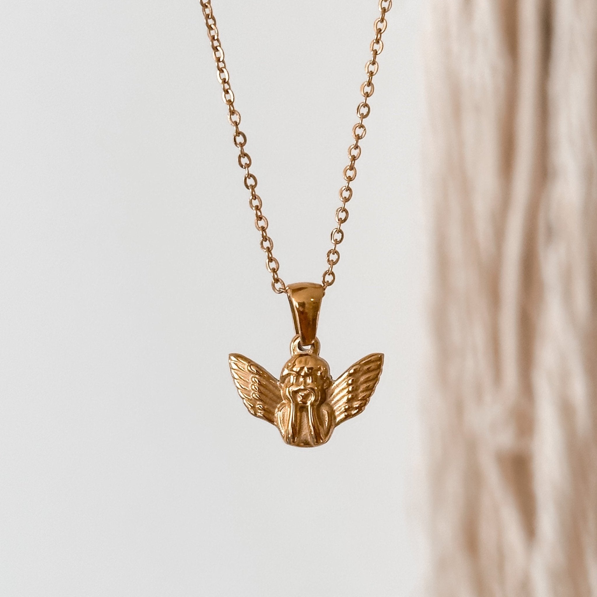 8K Gold Angel Necklace hanging on a display, showcasing the delicate angel charm.