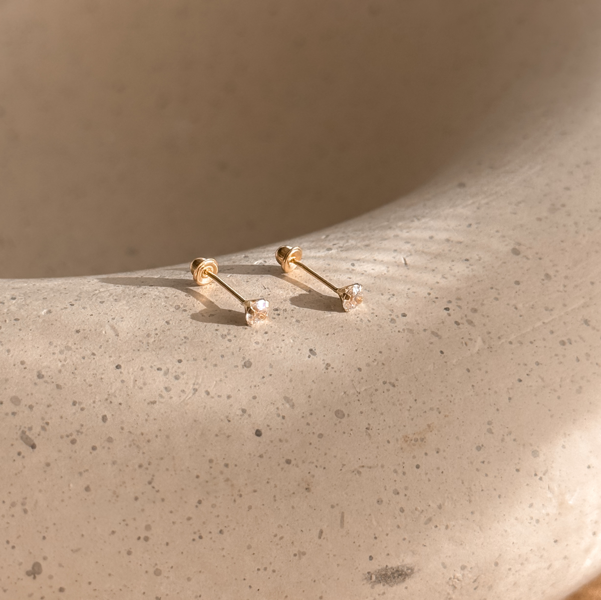 3mm CZ solitaire solid gold studs with screw backs on a stone dish, side view – Liv Aura
