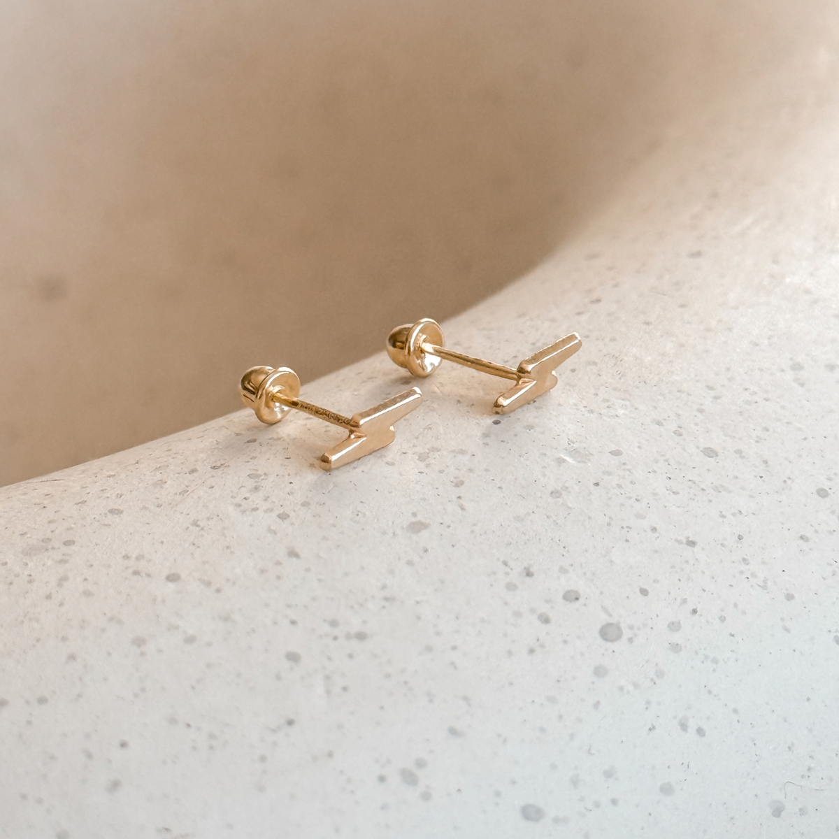 10K solid gold lightning bolt stud earrings with screw backs on a speckled stone dish – Liv Aura