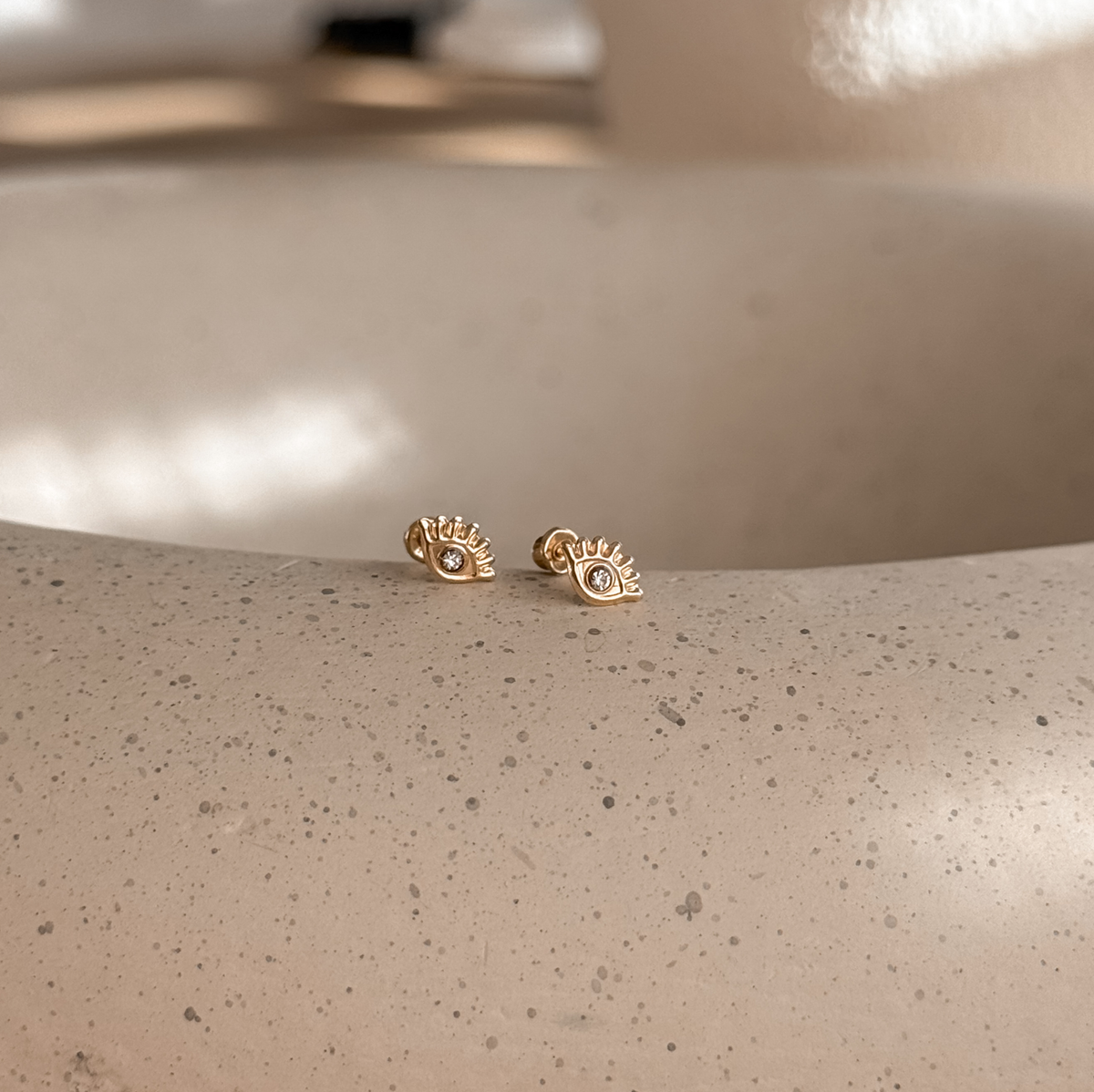 10K solid gold evil eye studs with screw backs on a stone dish, side view – Liv Aura