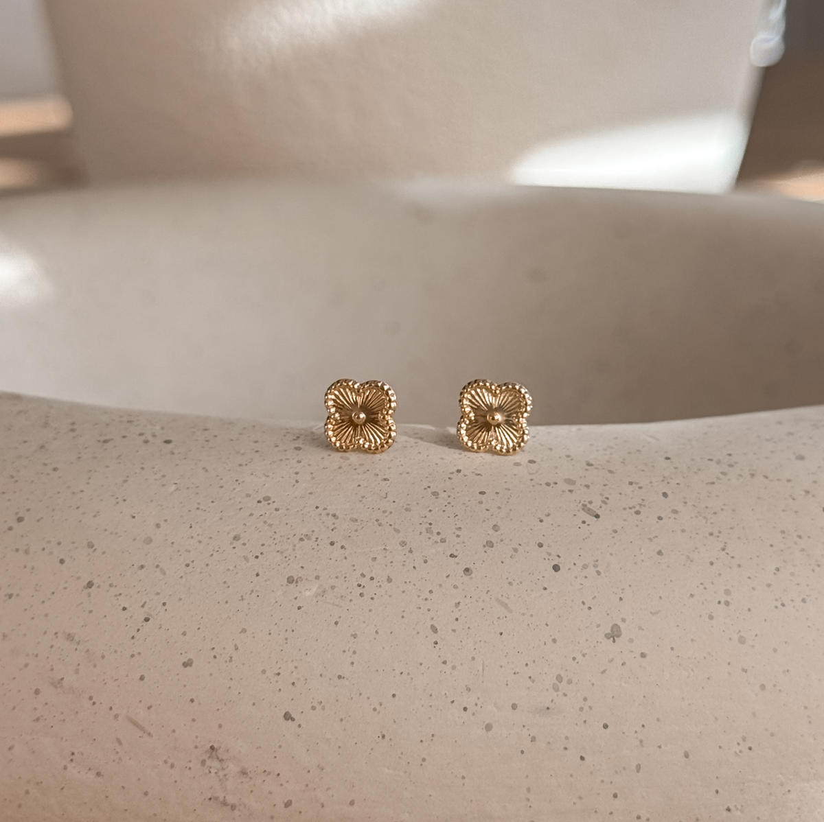10K solid gold clover flower stud earrings on a speckled stone dish – Liv Aura