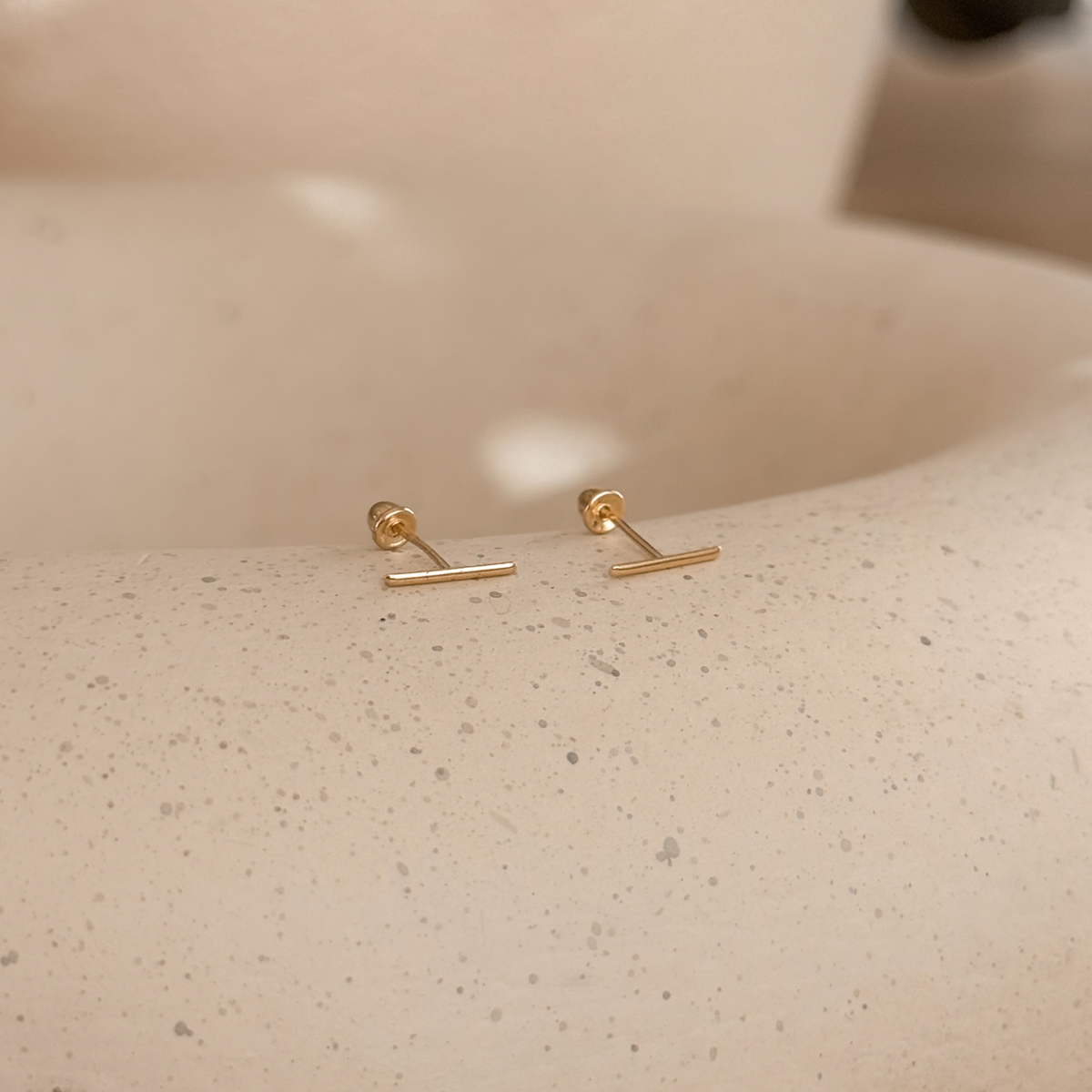 10K solid gold bar stud earrings with screw backs on a speckled stone dish – Liv Aura