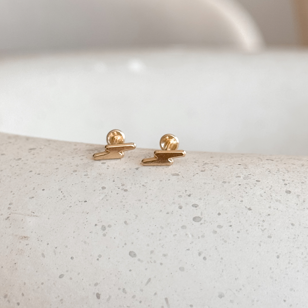 10K solid gold lightning bolt stud earrings on a stone dish, side view of the screw backs – Liv Aura