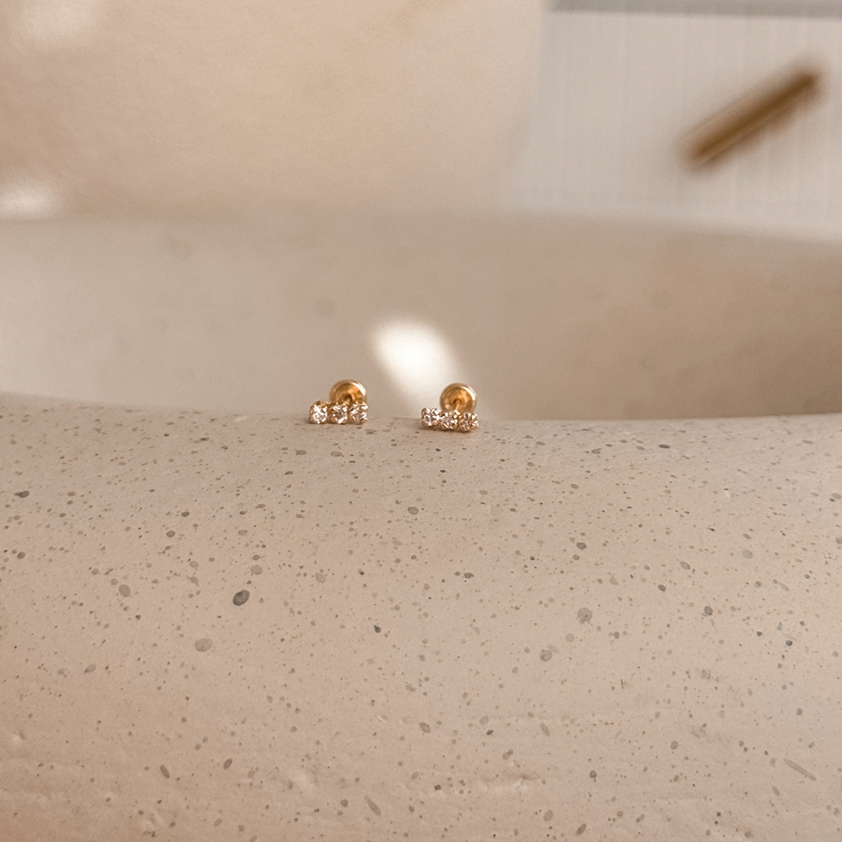 10K solid gold white CZ bar stud earrings with screw backs on a speckled stone dish – Liv Aura