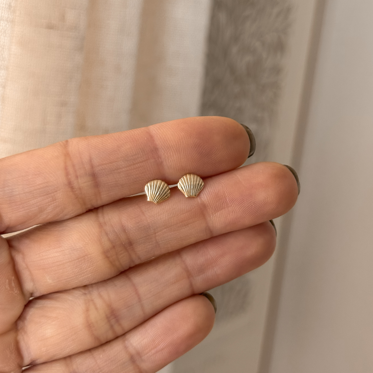 10K solid gold seashell stud earrings held in hand to show the size – Liv Aura