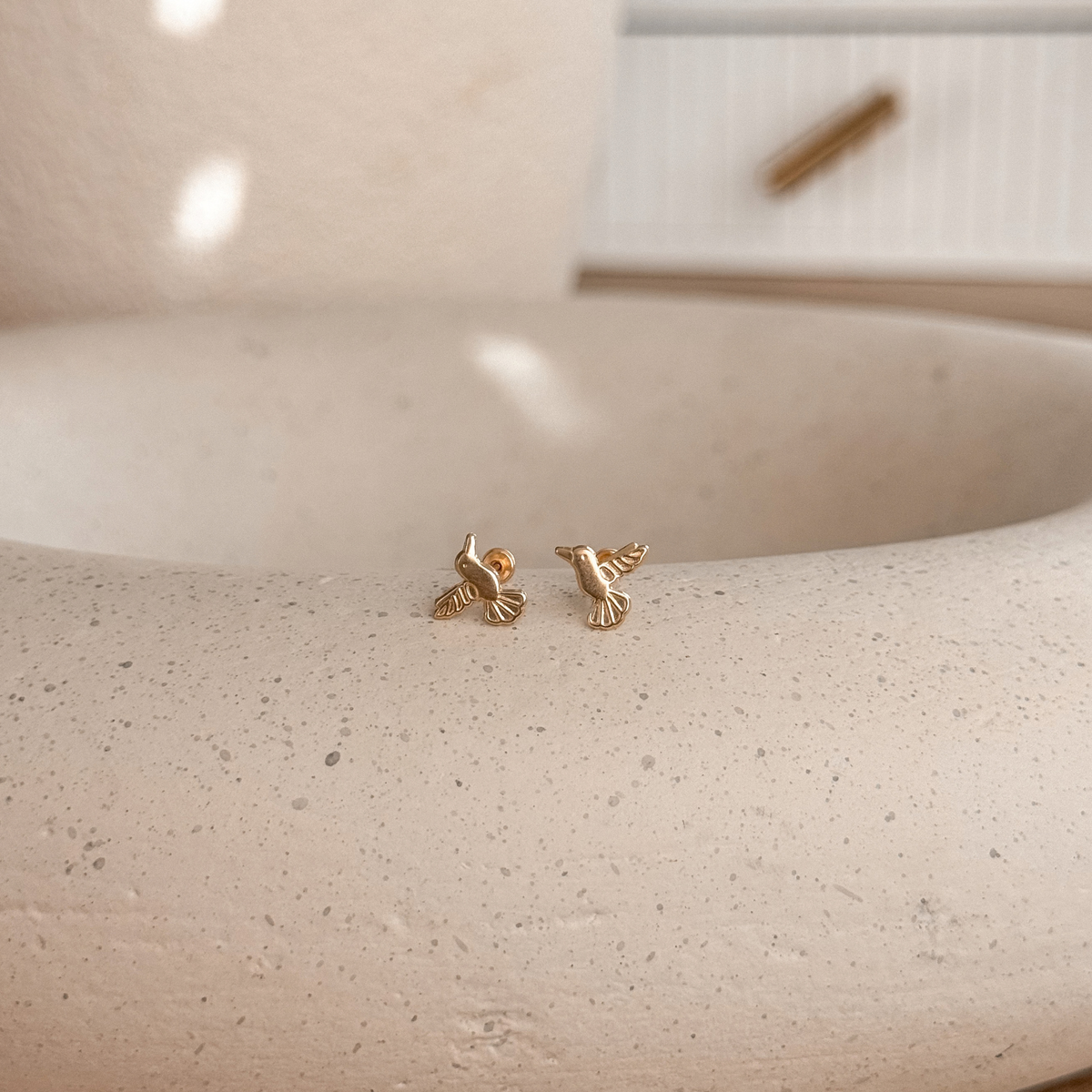 10K solid gold hummingbird stud earrings on a stone dish, side view – Liv Aura