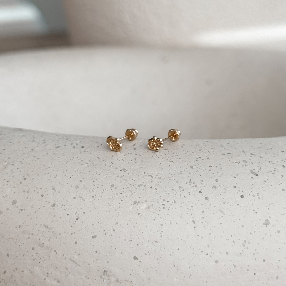 10K solid gold mini hamsa hand stud earrings with screw backs on a speckled stone dish – Liv Aura