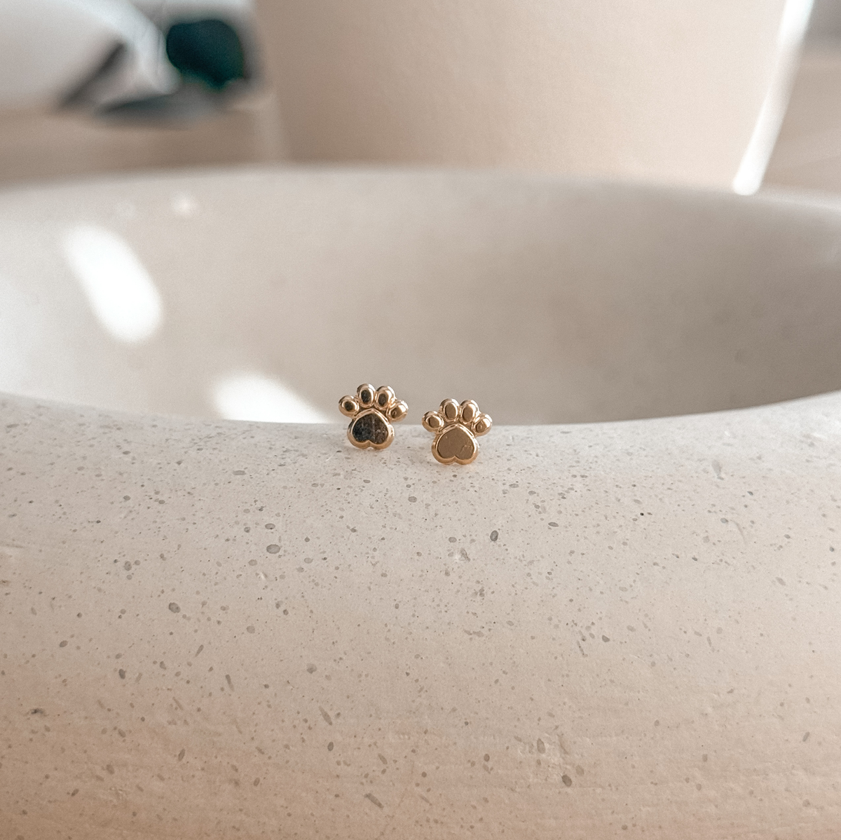 10K solid gold paw print studs with screw backs on a stone dish, side view – Liv Aura