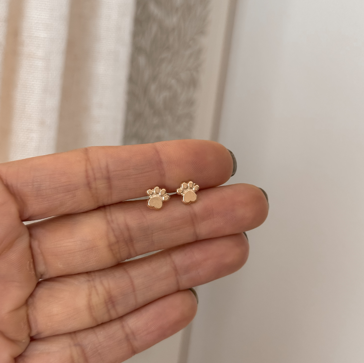 10K solid gold paw print stud earrings held in hand to show the size – Liv Aura