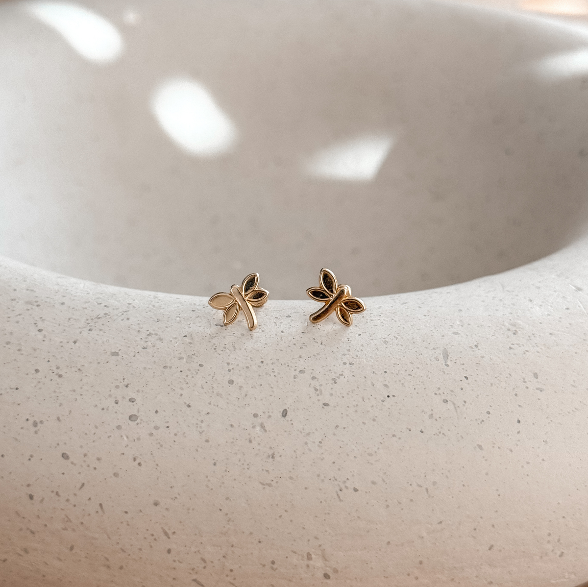 10K solid gold dragonfly stud earrings on a speckled stone dish – Liv Aura