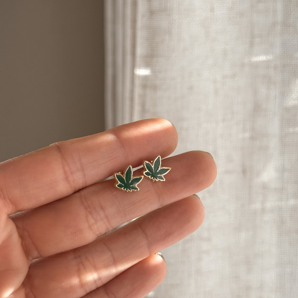 10K solid gold green leaf stud earrings held in hand to show the size – Liv Aura