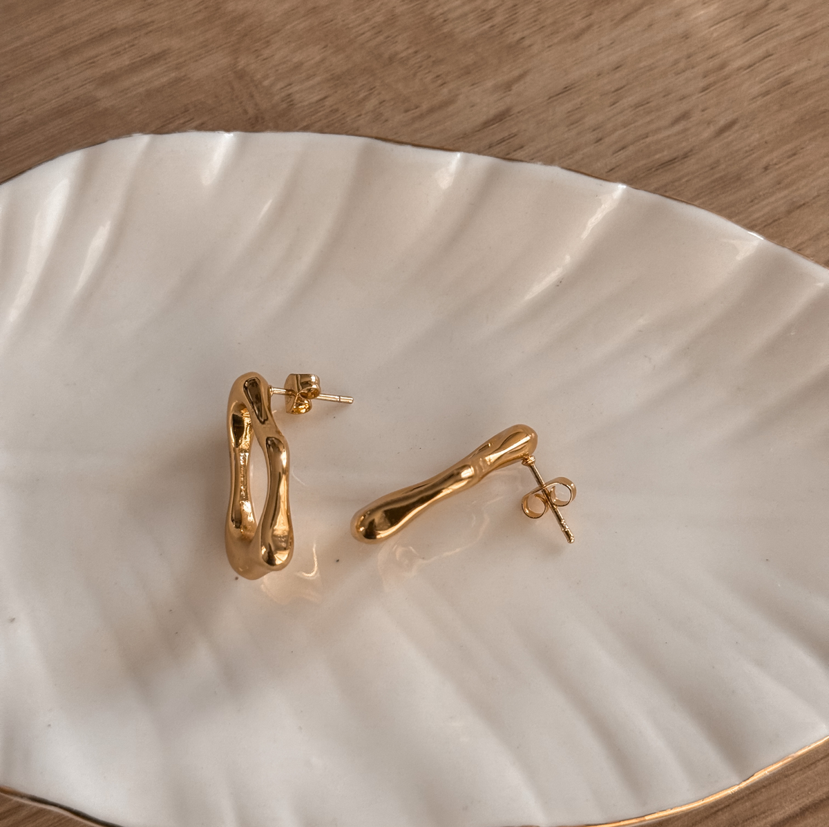 Gold organic open stud earrings showing the posts, side view on a white dish – Liv Aura