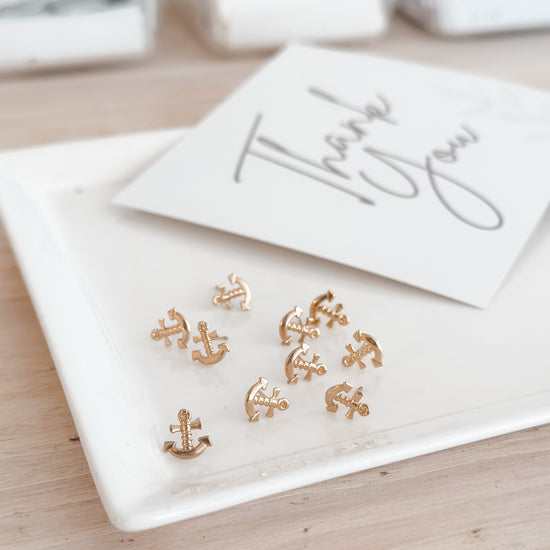Yellow anchor stud earring on a white plate