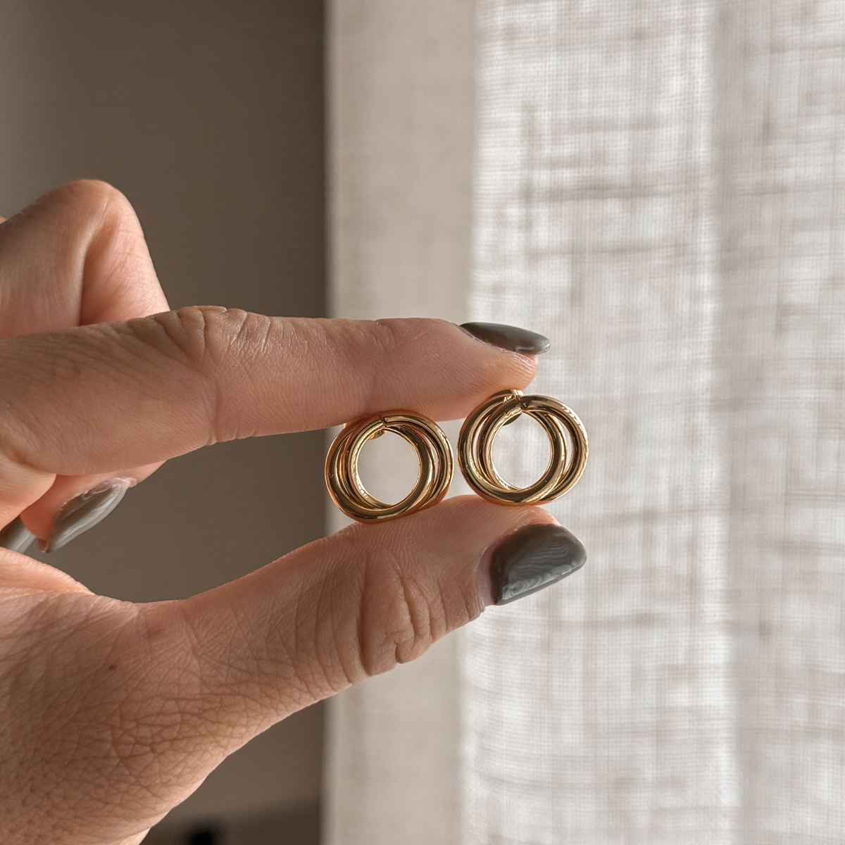 Gold circle stud earrings held in hand – Liv Aura