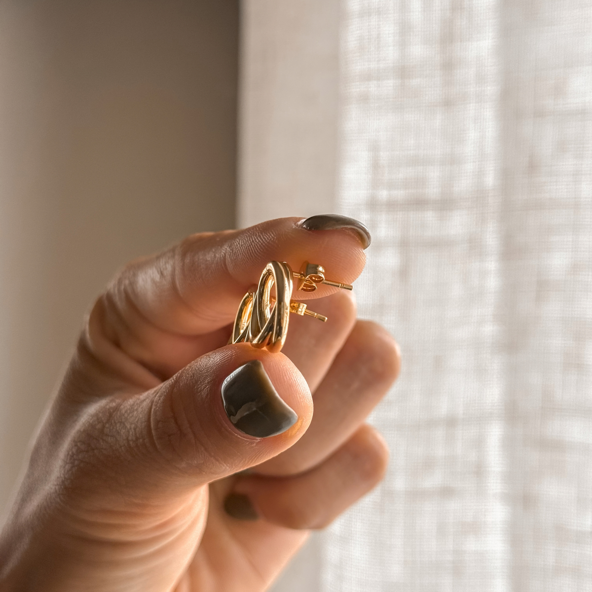 Gold circle stud earring held in hand, side view – Liv Aura
