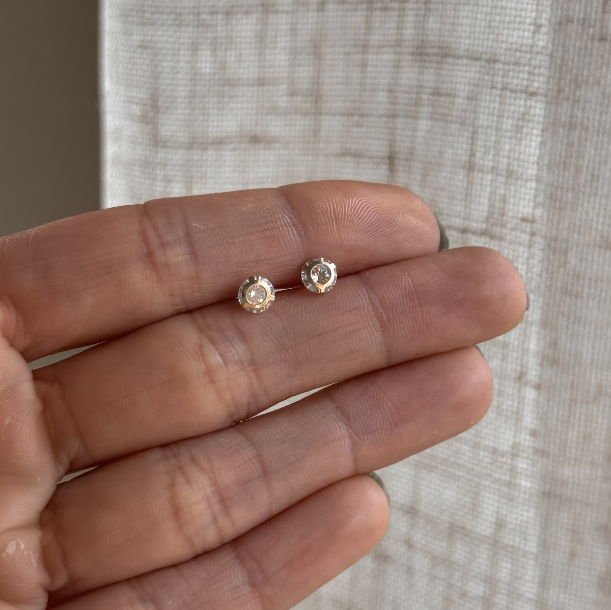 10K solid gold 5mm round CZ stud earrings held in hand to show the size – Liv Aura