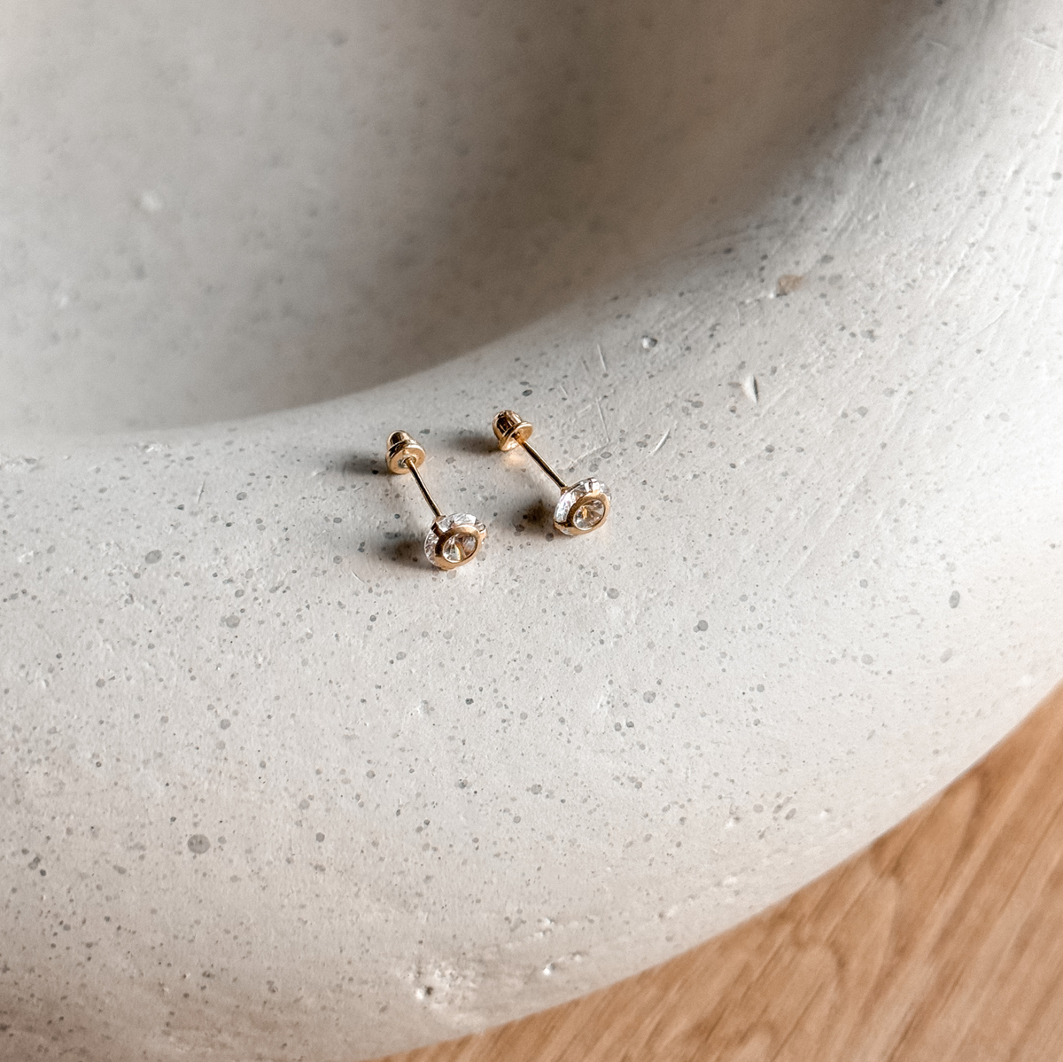 5mm round CZ solid gold studs with screw backs on a stone dish, side view – Liv Aura