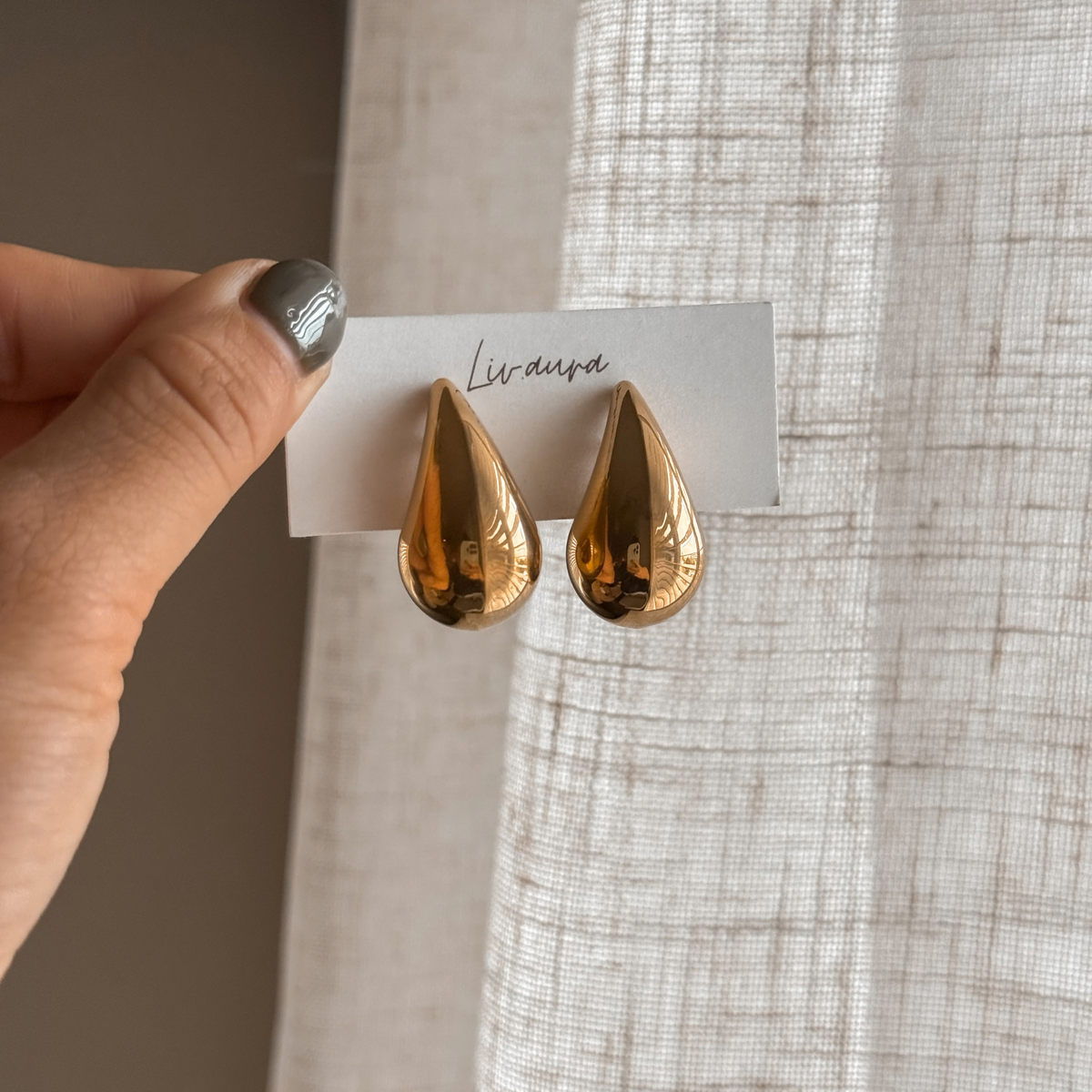 Gold teardrop earrings on a Liv Aura earring card held in hand – Liv Aura