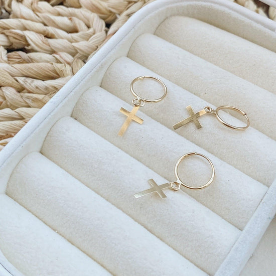 A stunning pair of Hipster style hoop earrings. Perfect to match any outfit, these earrings are great for everyday wear and will never go out of style. The perfect gift for the creative person in your life, who loves wearing trendy jewellery. These cross hoops are made from 10K gold and come with a small charm detailing a cross