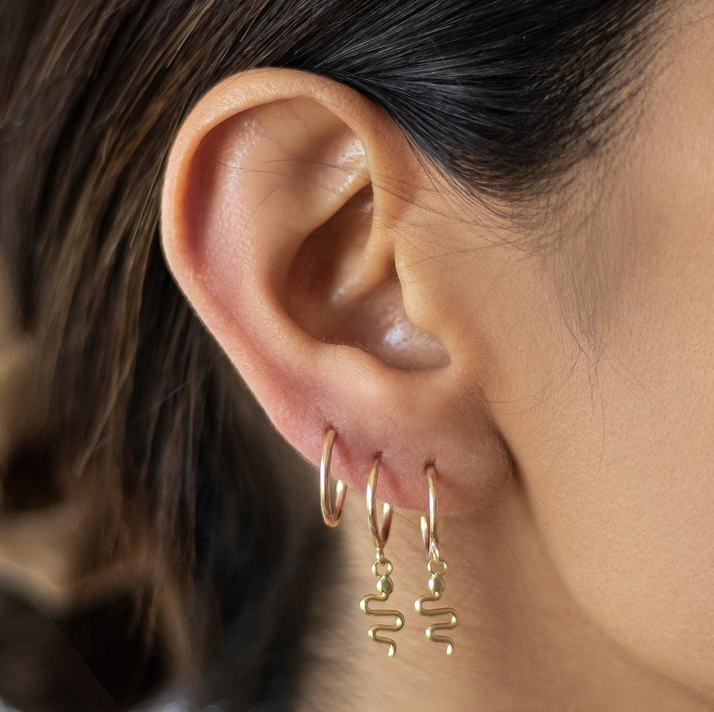 Load image into Gallery viewer, The Snake Earrings are trendy and unique. 10K Gold Hoop Earrings with a Gold Snake Charm in the center, these snake earrings are sure to make you stand out in a crowd. Ultra stylish Huggie hoop earrings that will look great on anyone’s ears!

