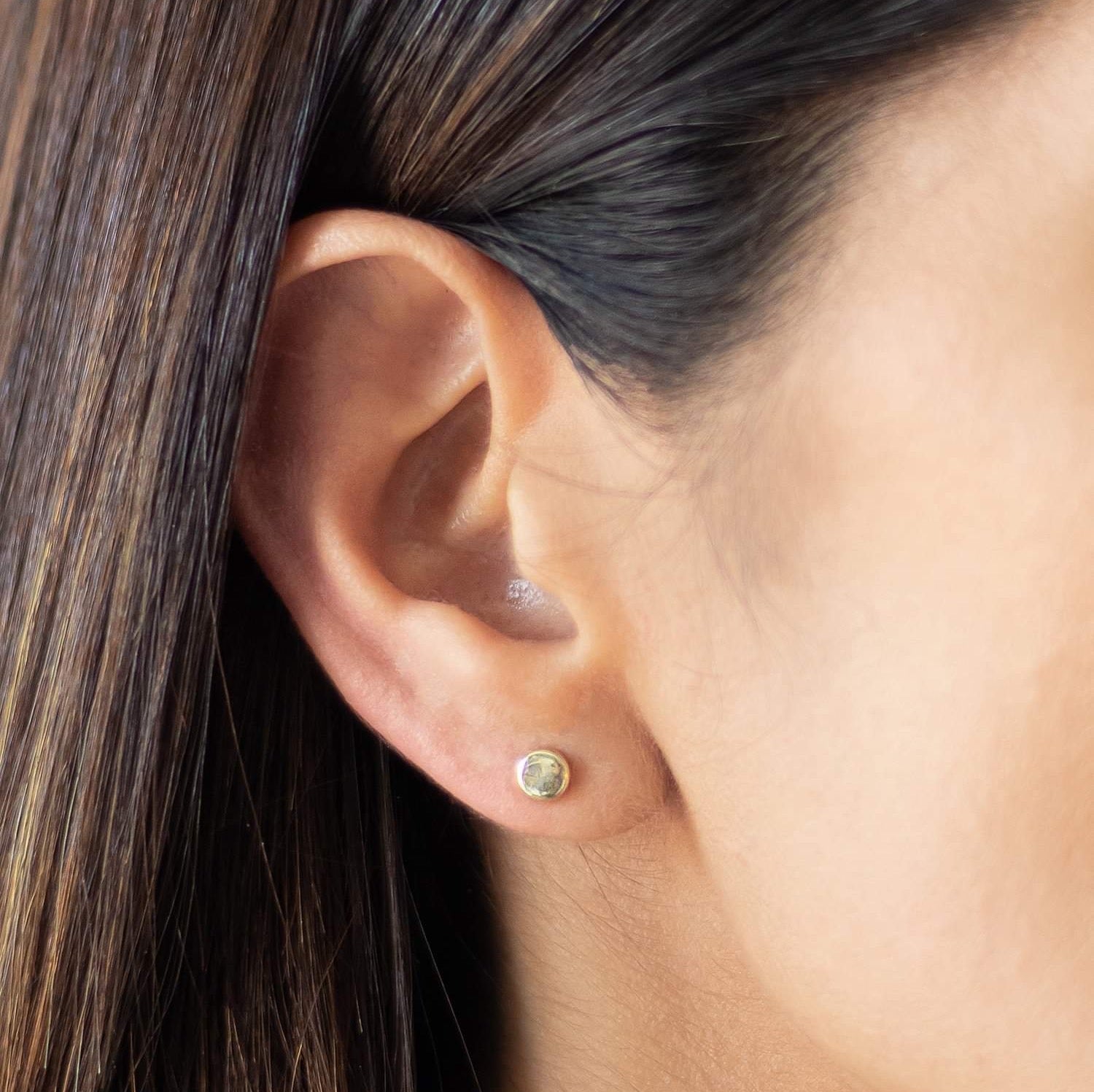 Model wearing small gold dot earrings on the lobe – screw back, hypoallergenic design