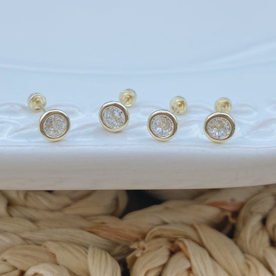 This 14K solid gold bezel stud earring is perfect for everyday wear. The simple design makes this earring versatile enough to wear with any outfit and the 4mm bezel size gives it a delicate look that adds just the right amount of sparkle.
