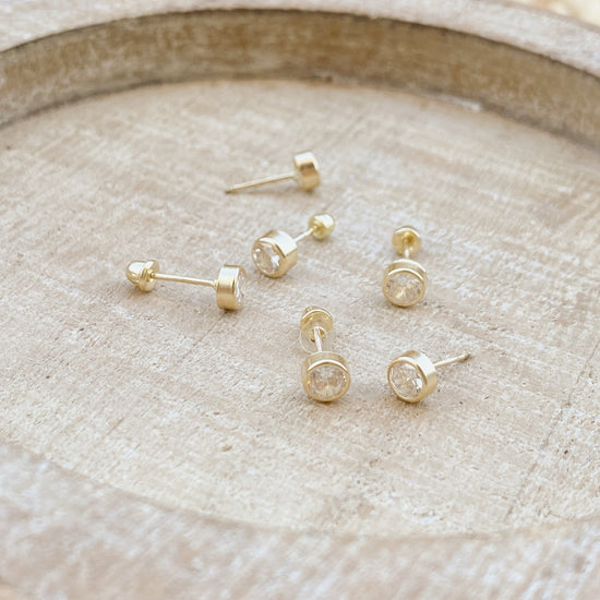 Load image into Gallery viewer, These 14k gold bezel stud earrings are perfect for everyday wear. These earrings are delicate and lightweight studs that are easily worn in both hoop and screw back. The gold is high quality, meaning they won&amp;#39;t dull over time or change color.
